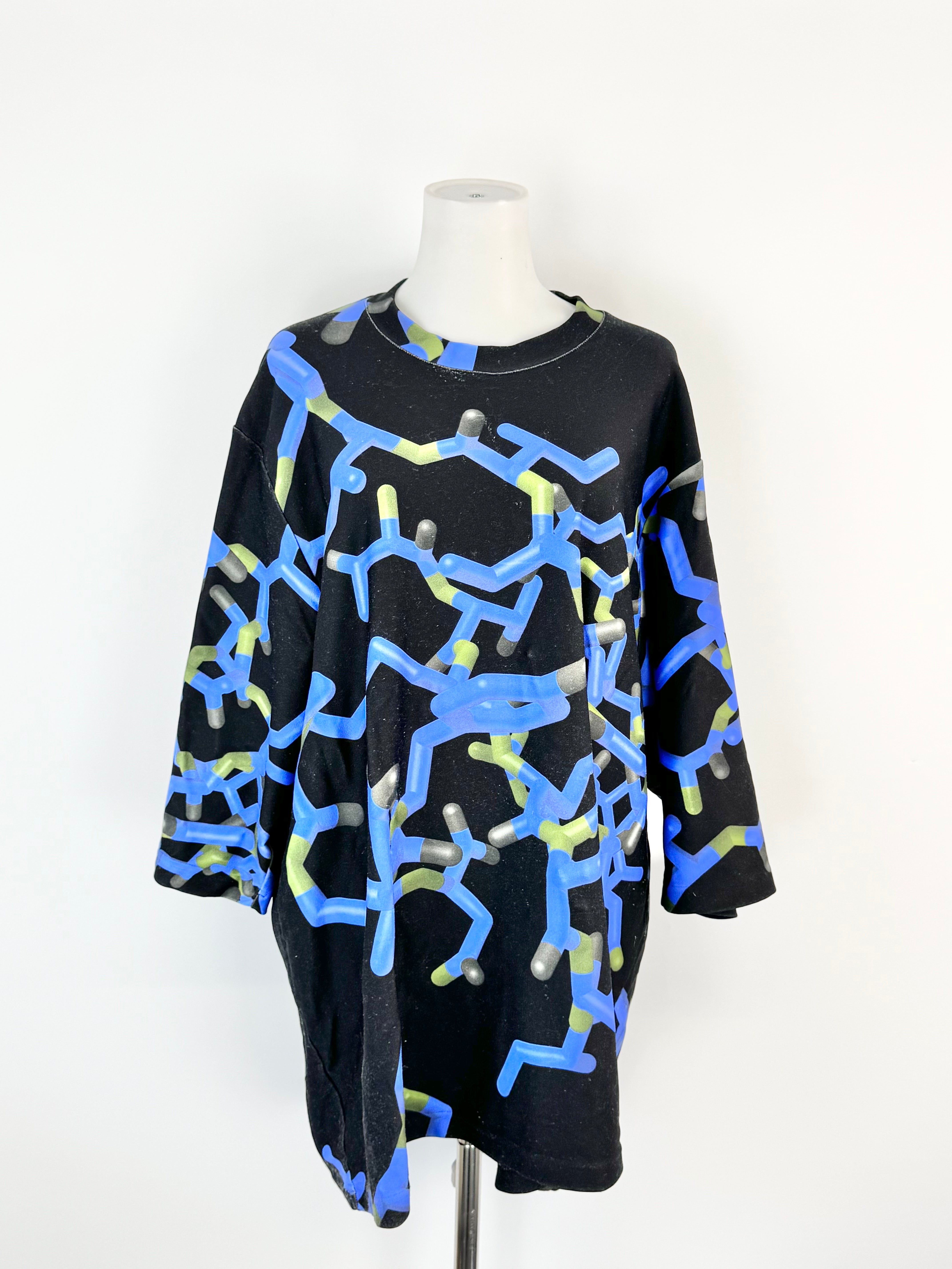 Black dress with blue and green abstract patterns on a mannequin against a white background