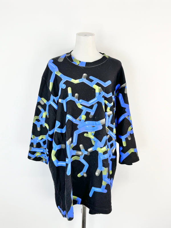 Black dress with blue and green abstract patterns on a mannequin against a white background