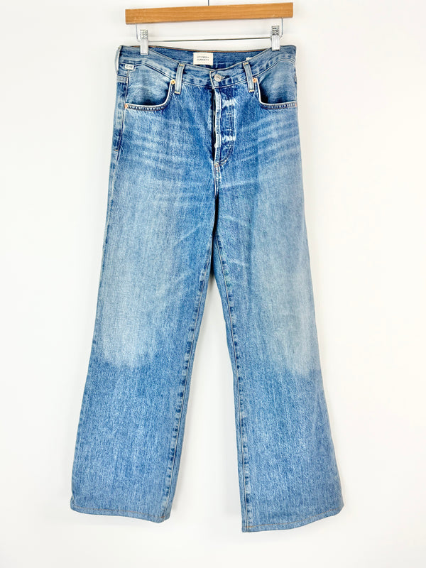Pair of blue jeans hanging on a white background