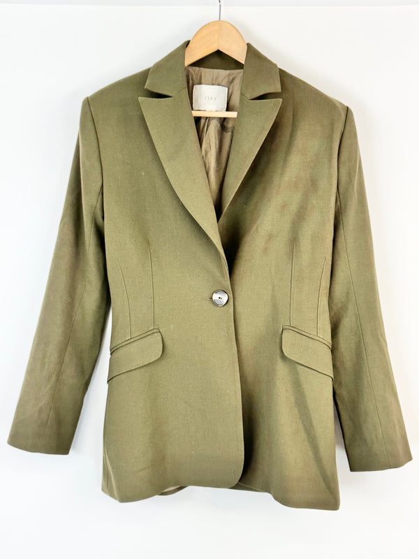 Green blazer on a wooden hanger against a white background