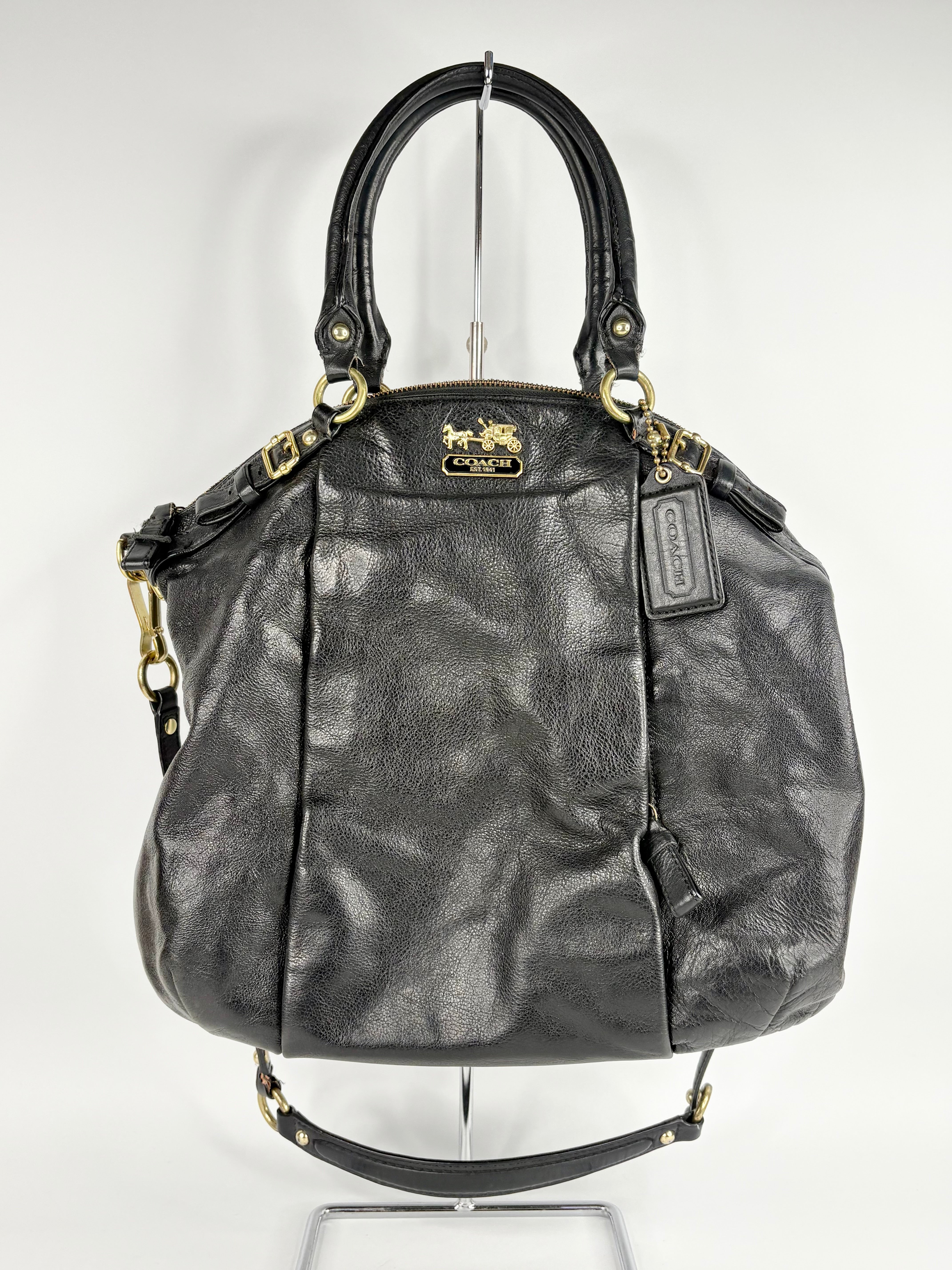 Black leather handbag with gold accents on a white background