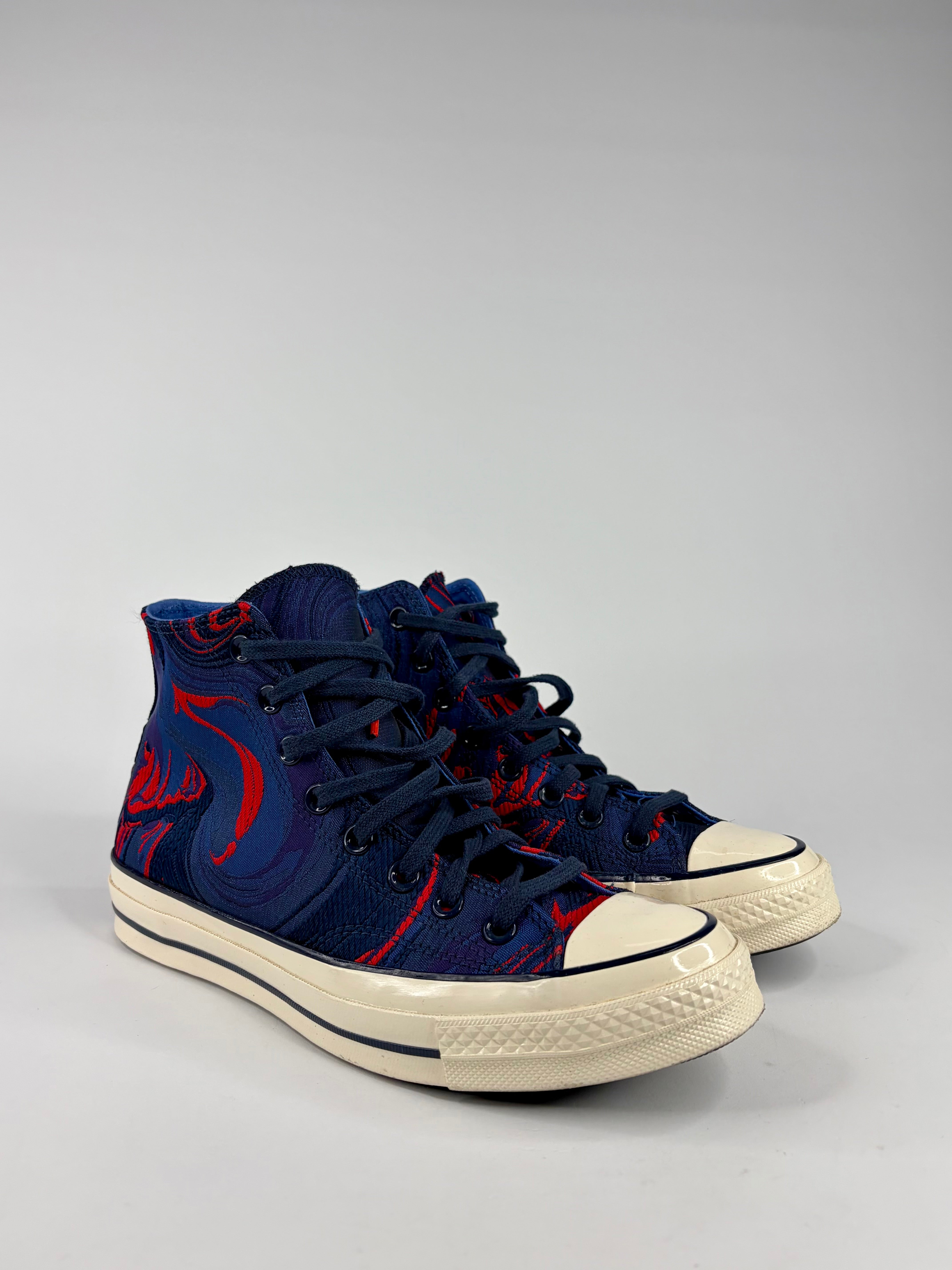 Navy high-top sneakers with red designs on a gray background
