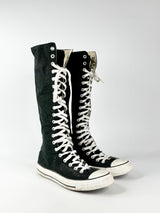 Black high-top sneakers with white laces on a light gray background