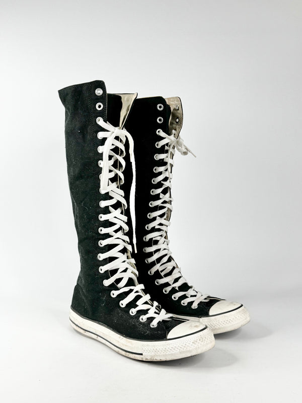 Black high-top sneakers with white laces on a light gray background