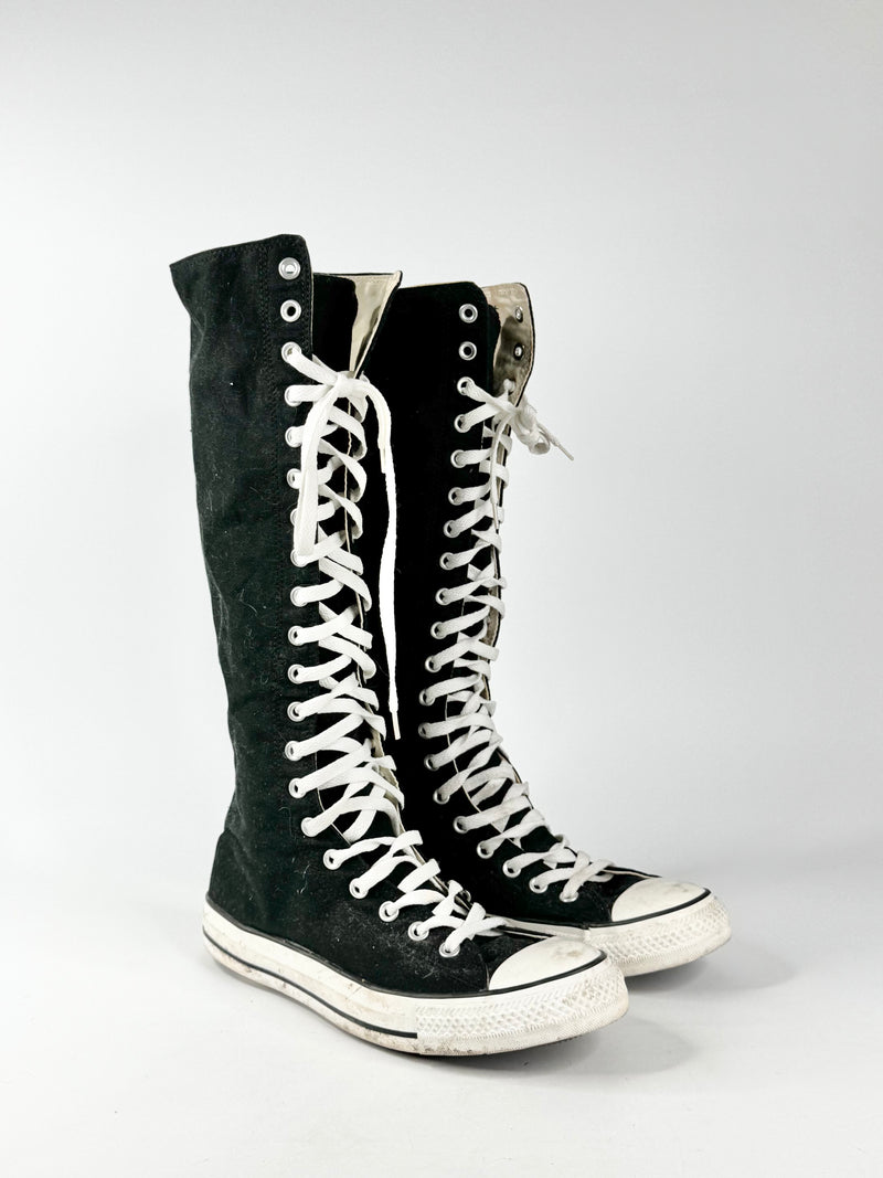 Black high-top sneakers with white laces on a light gray background