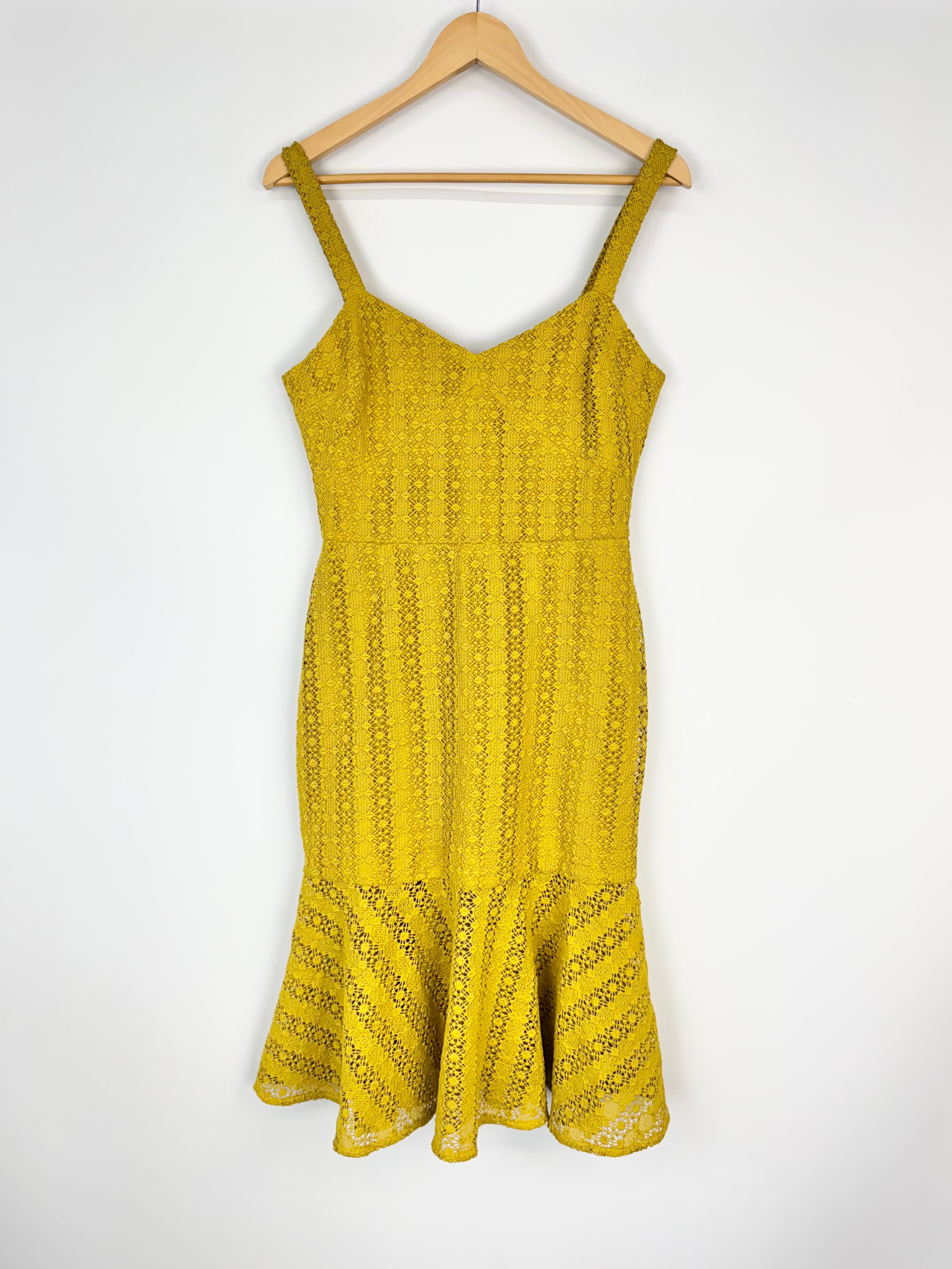 Yellow dress with lace details on a hanger against a white background