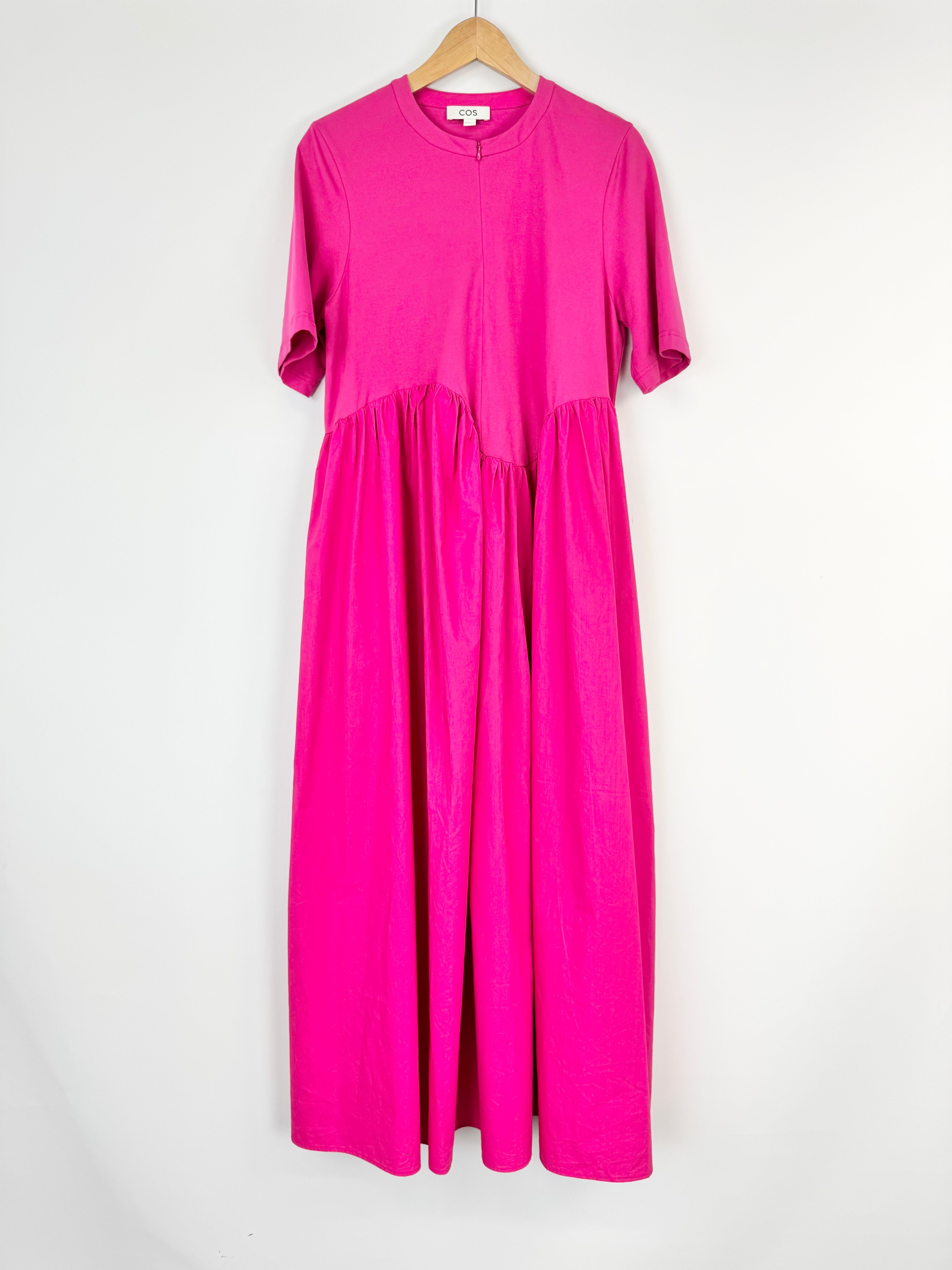 Pink dress on a hanger against a white background