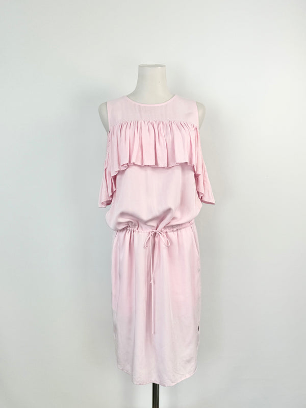 A pastel pink sleeveless dress with ruffled trim at the bust, a drawstring waist, and pockets, displayed on a mannequin.