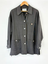 Black Country Road coat with button details on a wooden hanger against a white background