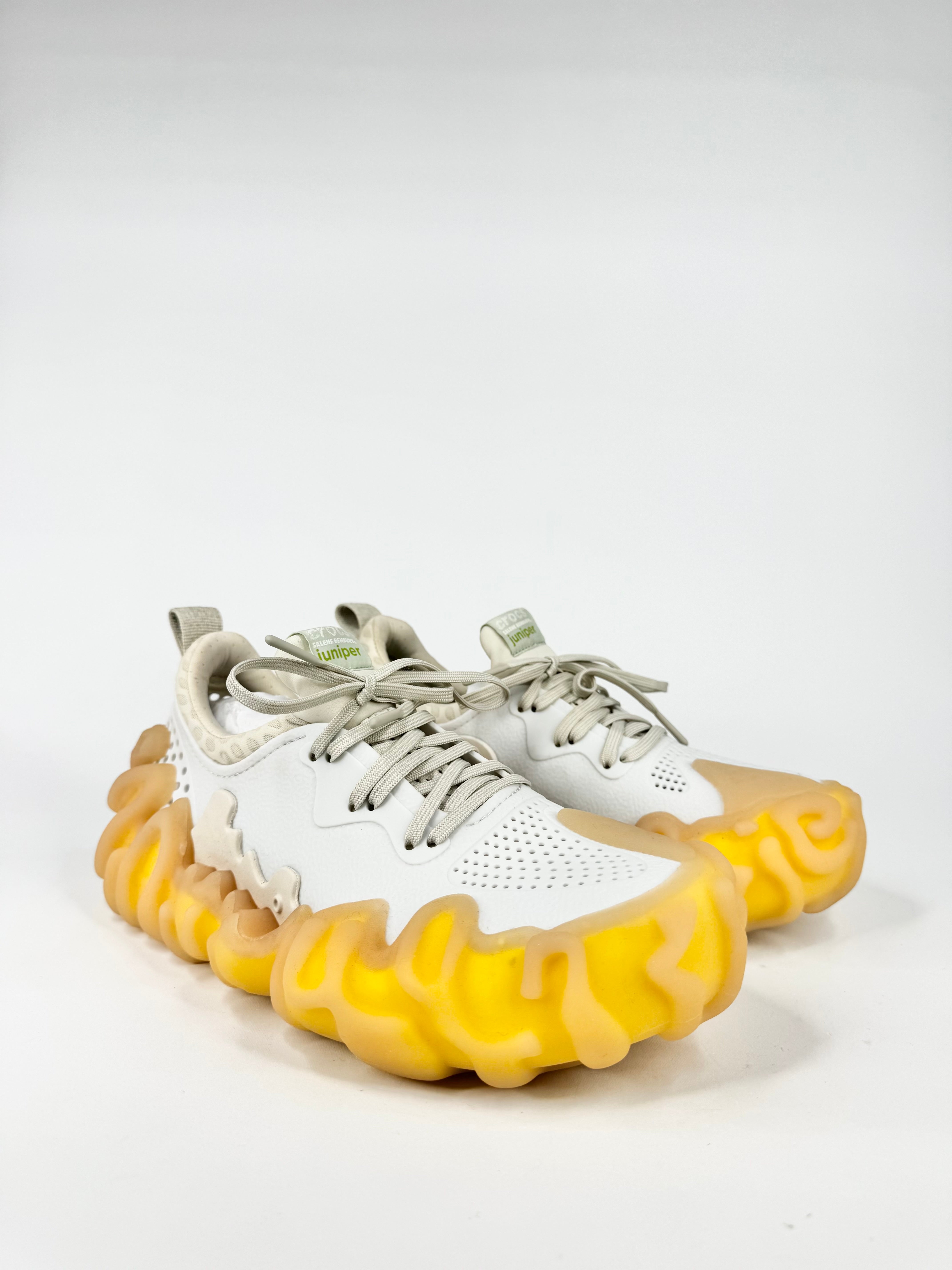 White sneakers with yellow soles on a light gray background