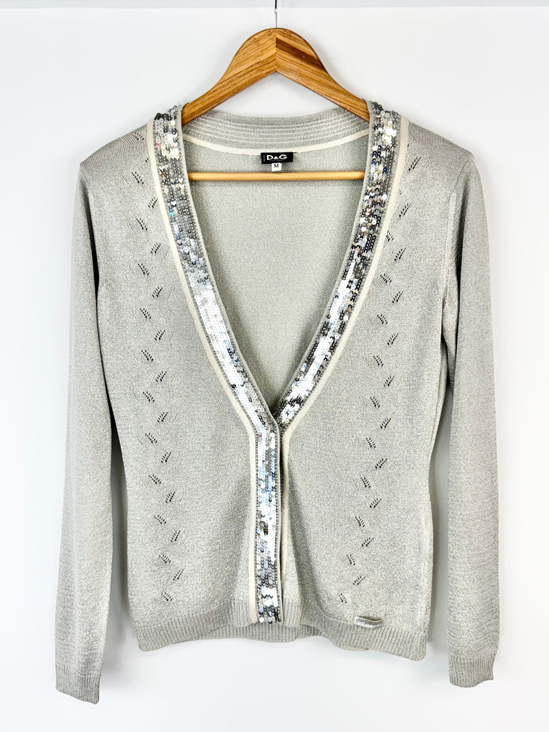 Gray cardigan with sequin details on a hanger against a white background