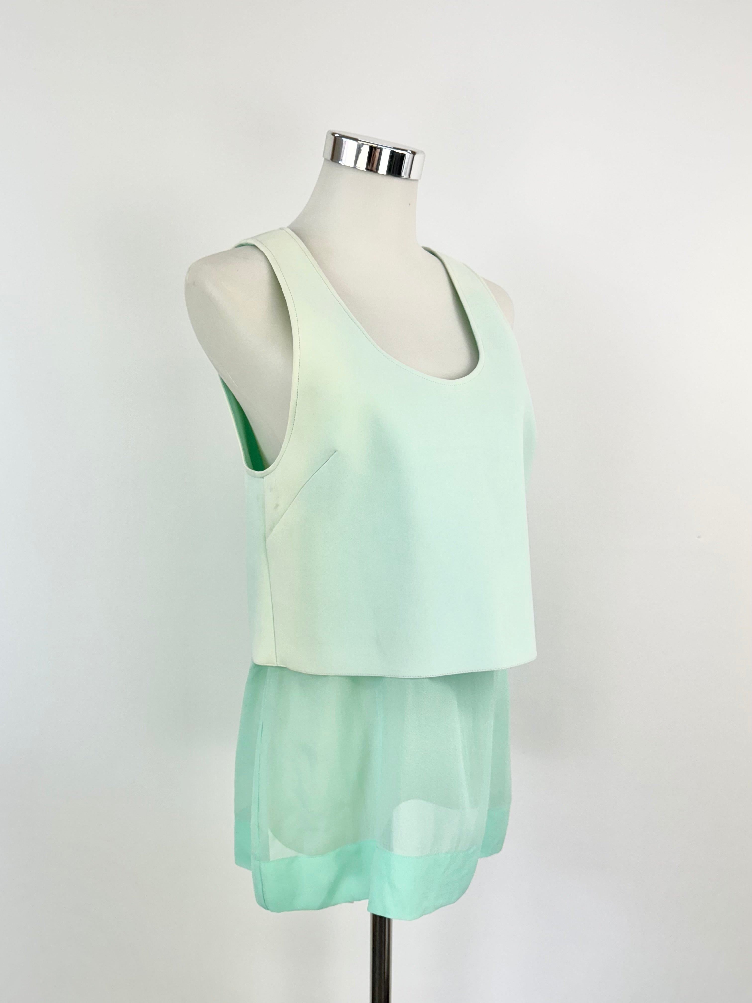 A sleeveless aqua shaded top on a mannequin, featuring an ovular scoop neckline and a combination of opaque and sheer fabric panels.