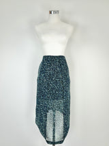 A blue and green sheer asymmetrical hem pencil skirt displayed on a mannequin. The mannequin is wearing a white top and the skirt has an asymmetrical hem design.