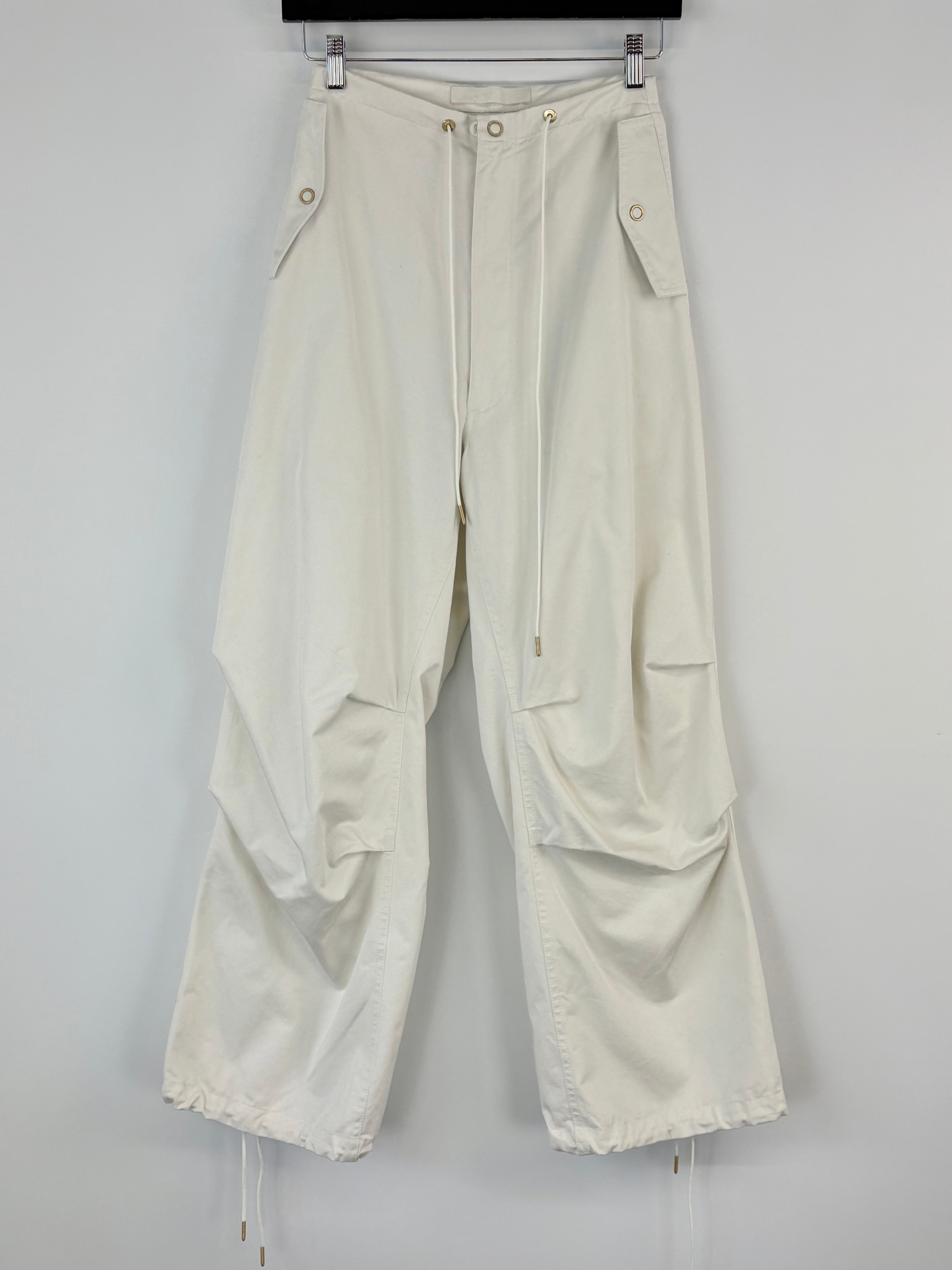 White pants hanging on a rack against a white background