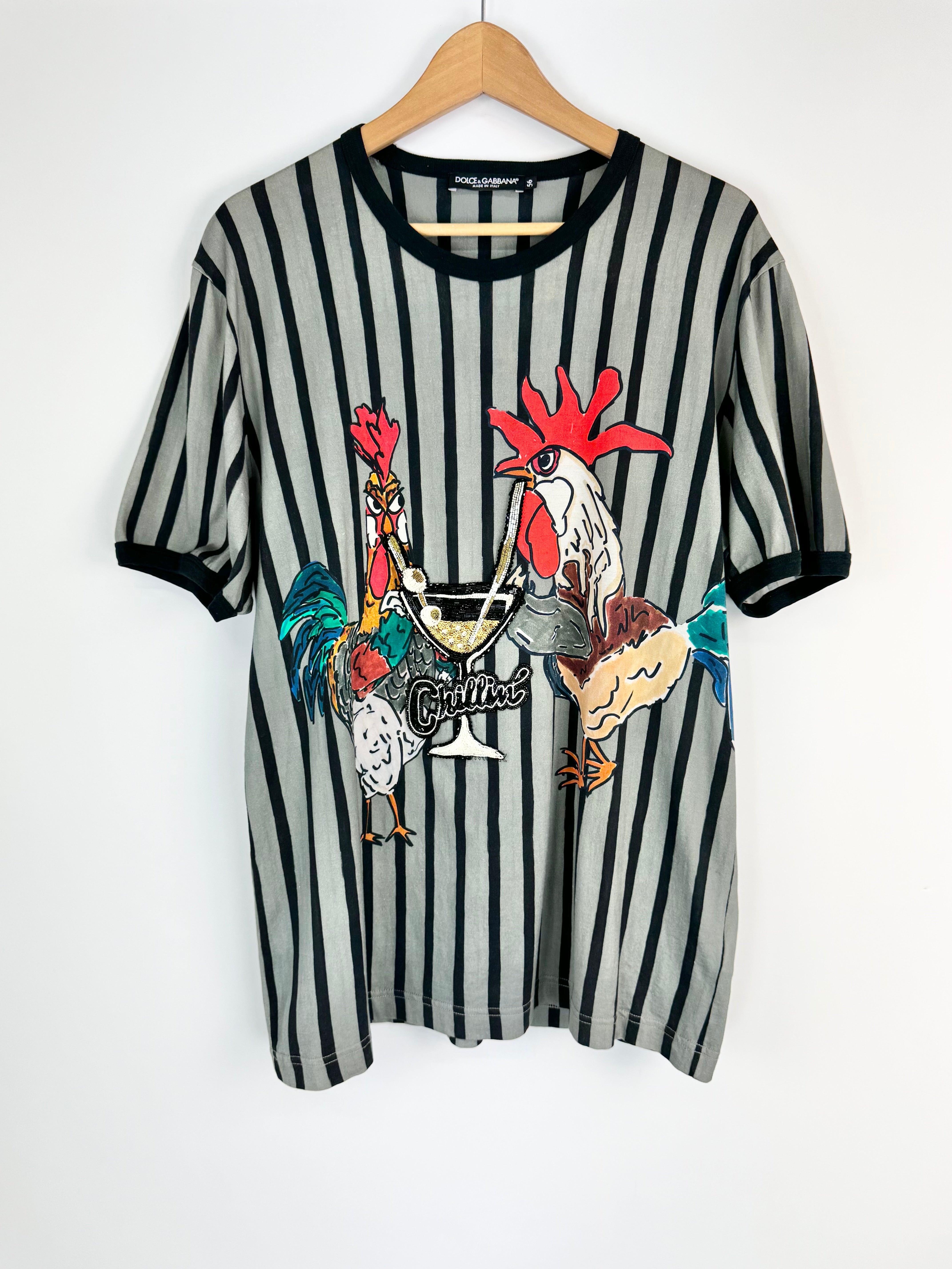 Striped t-shirt with rooster graphic on a hanger against a white background