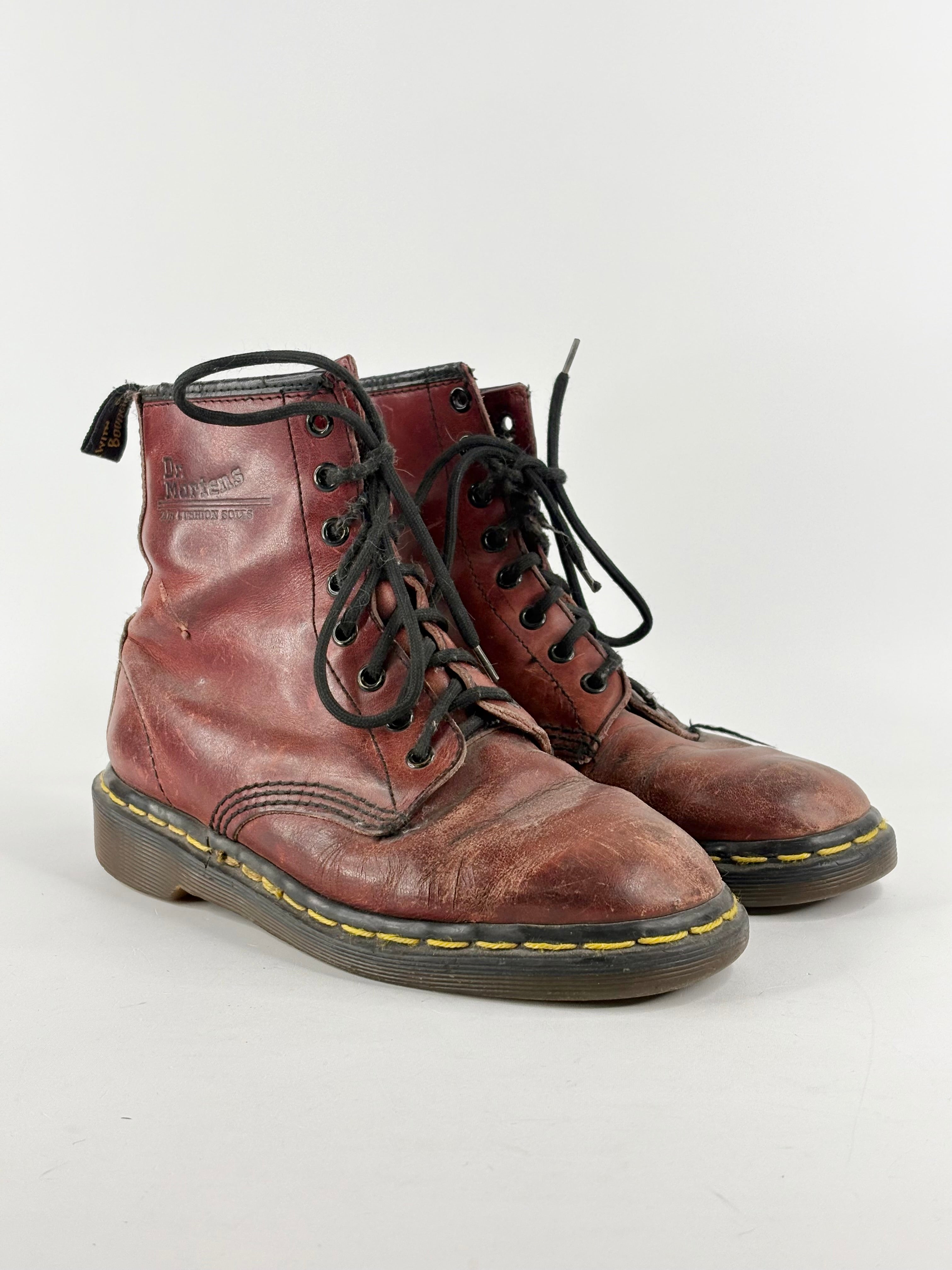 A pair of cherry red Dr. Martens lace-up boots with visible wear and black laces, on a white background.