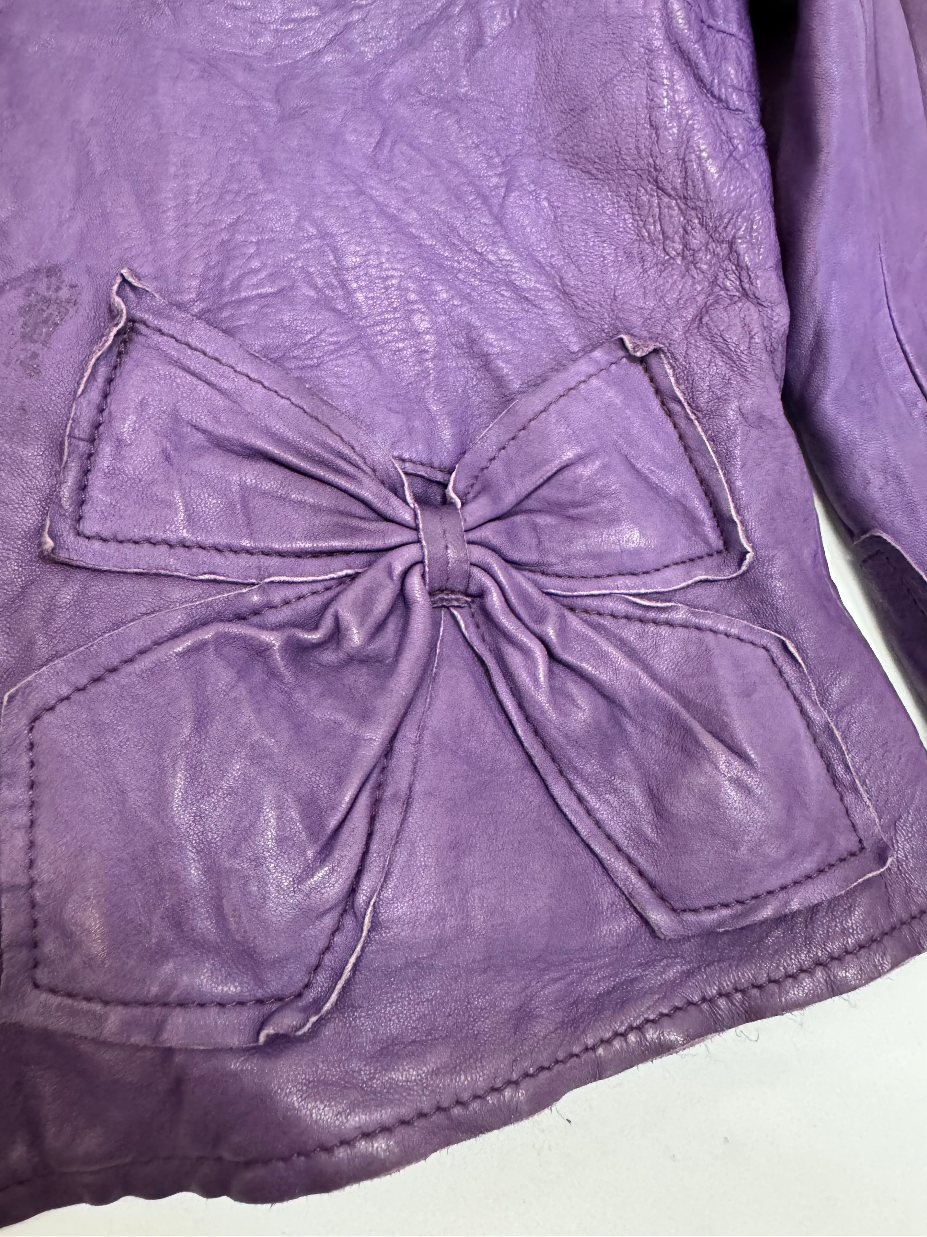 Purple leather jacket with a large bow detail on a white background