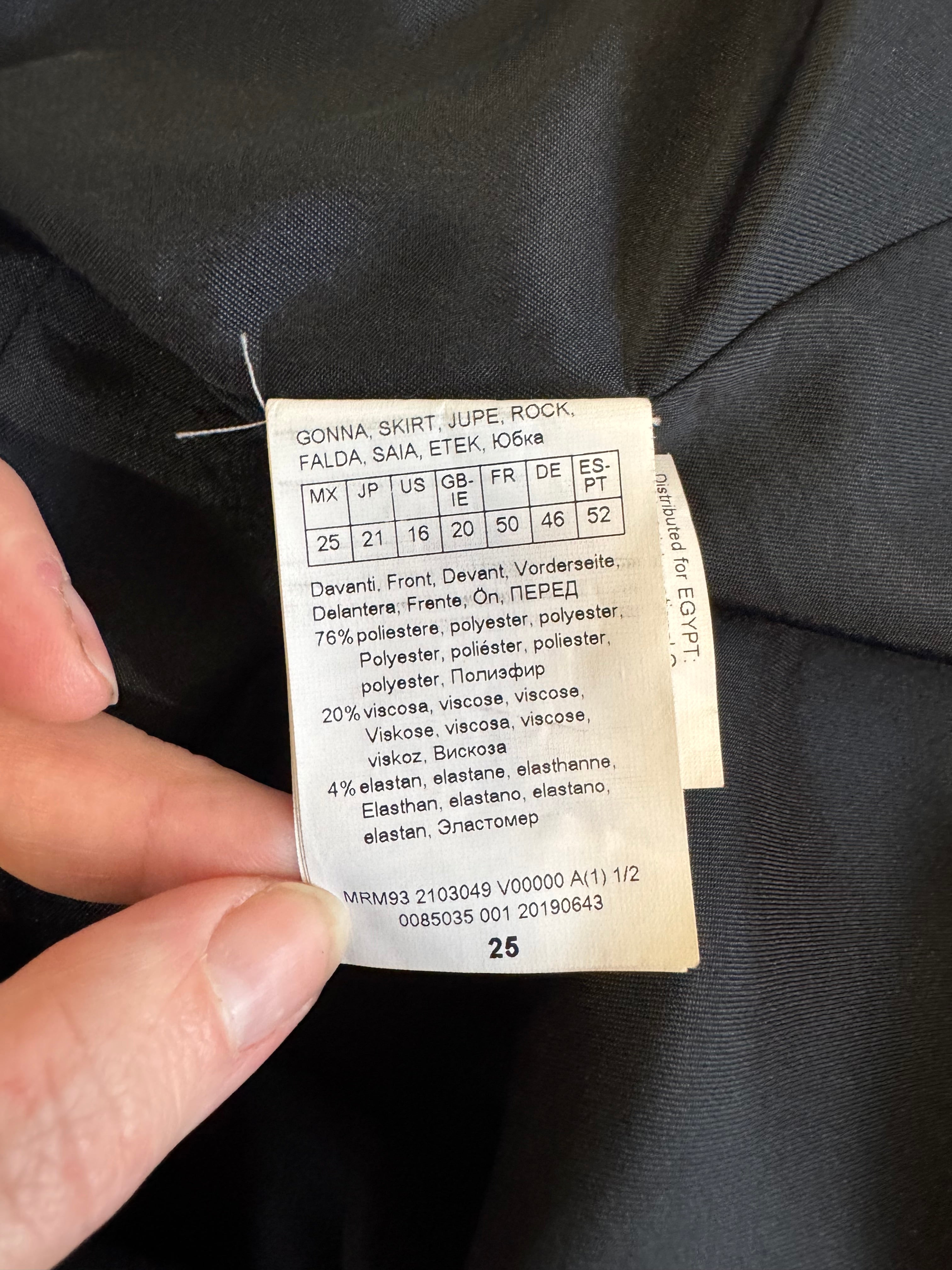 Clothing label held by a hand against a dark fabric background