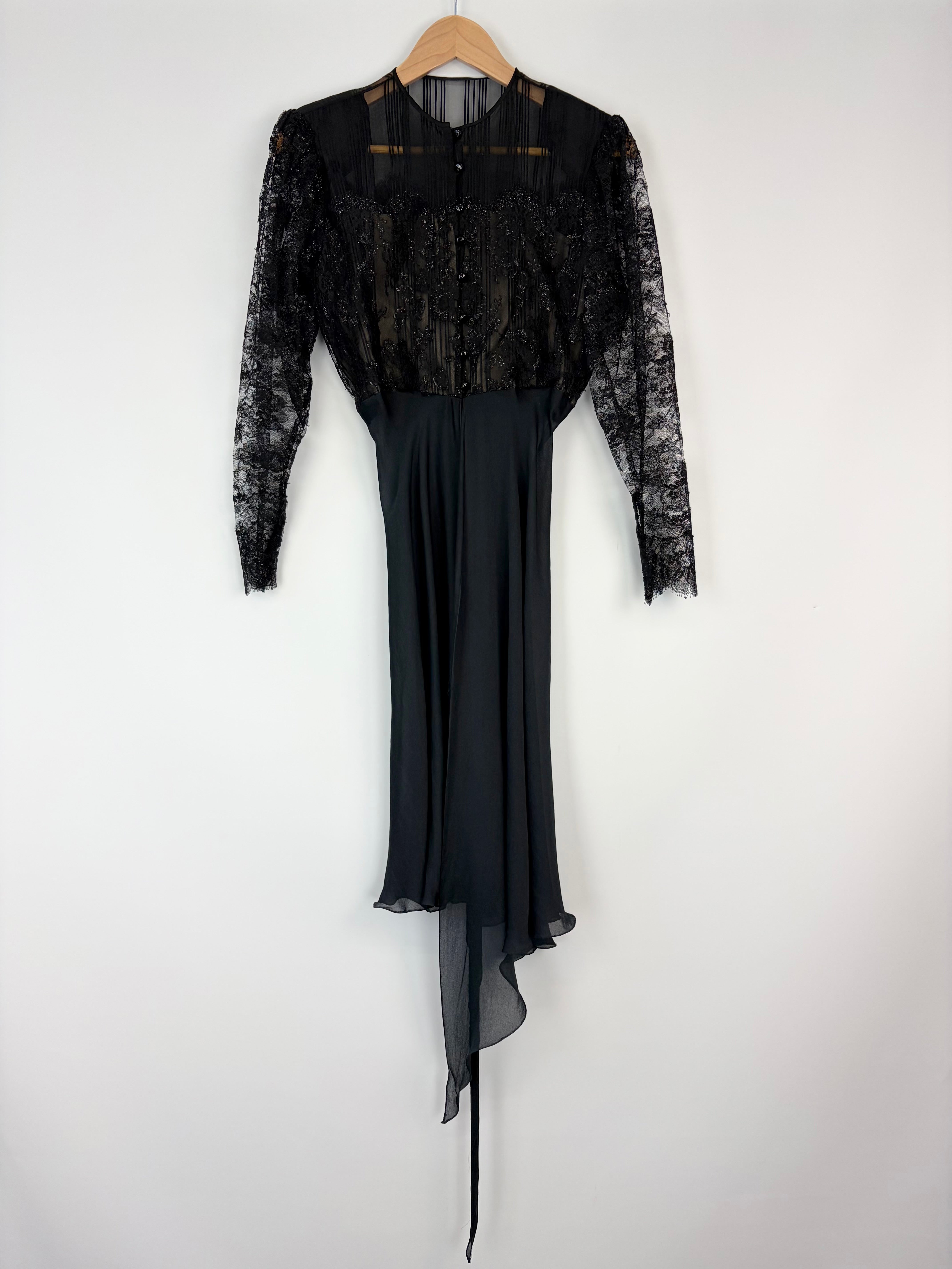 Black lace dress on a hanger against a white background