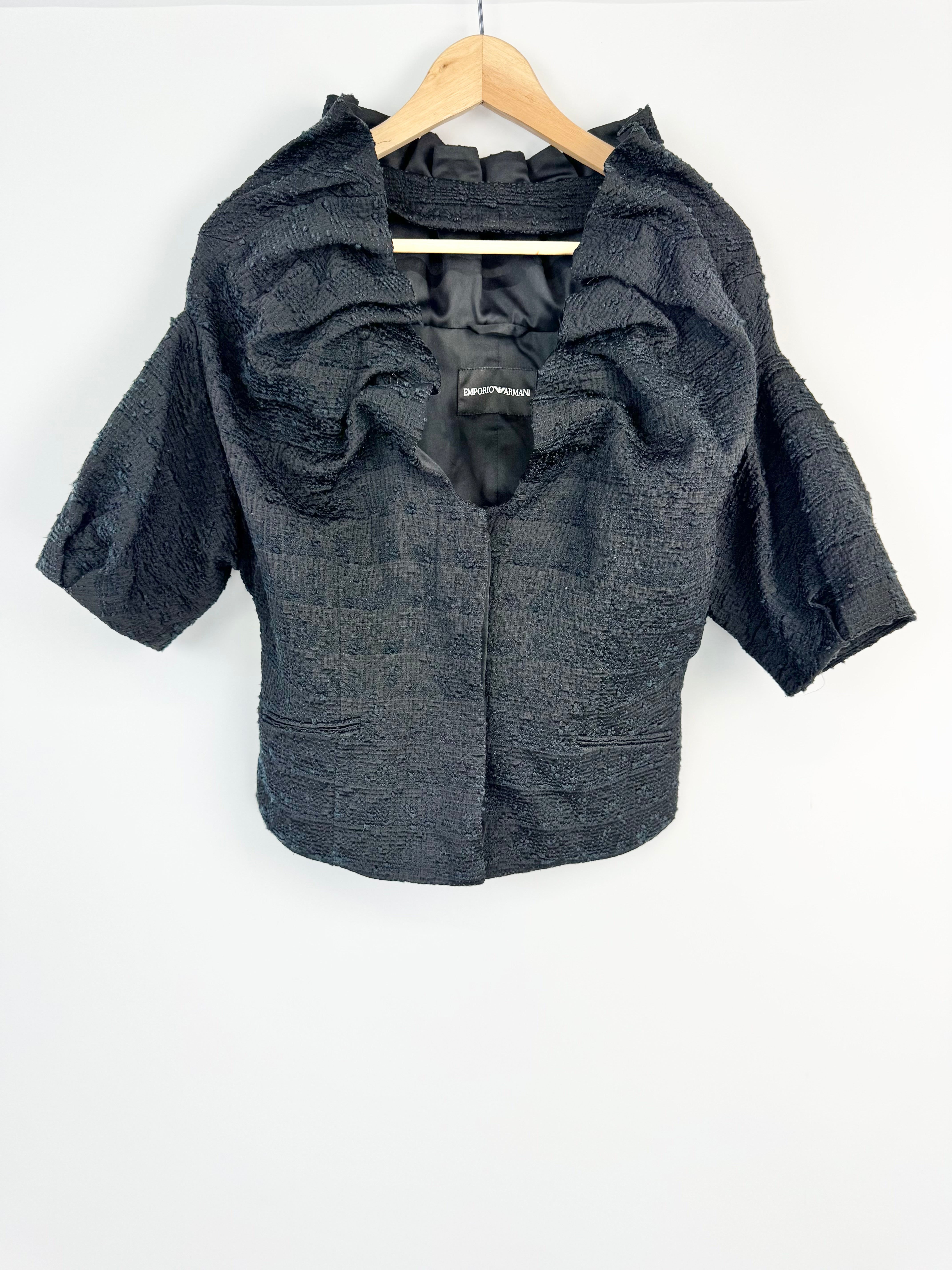 Dark Blue & black textured jacket on a wooden hanger against a white background