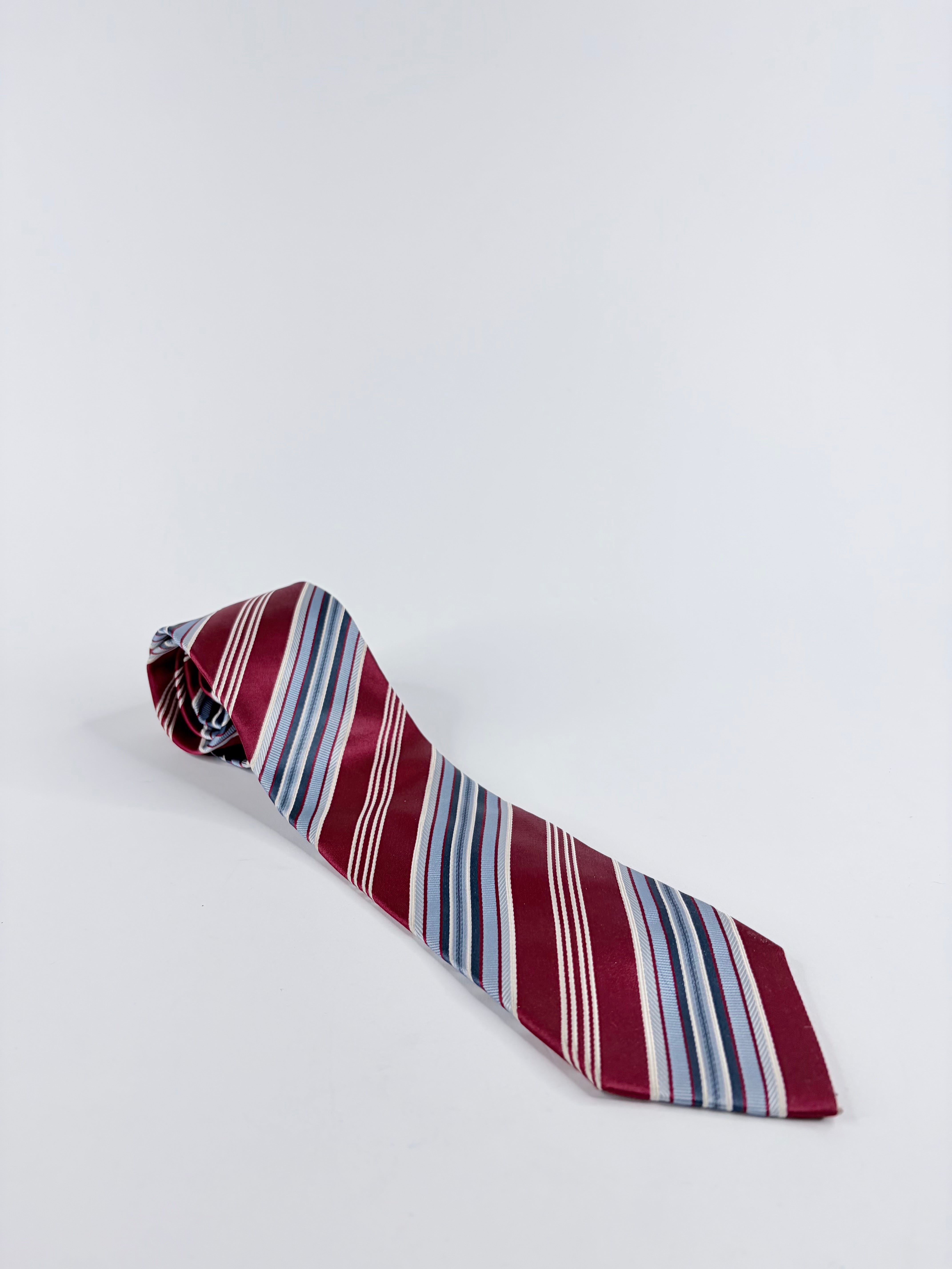 Striped tie with red, blue, and white pattern on a light gray background