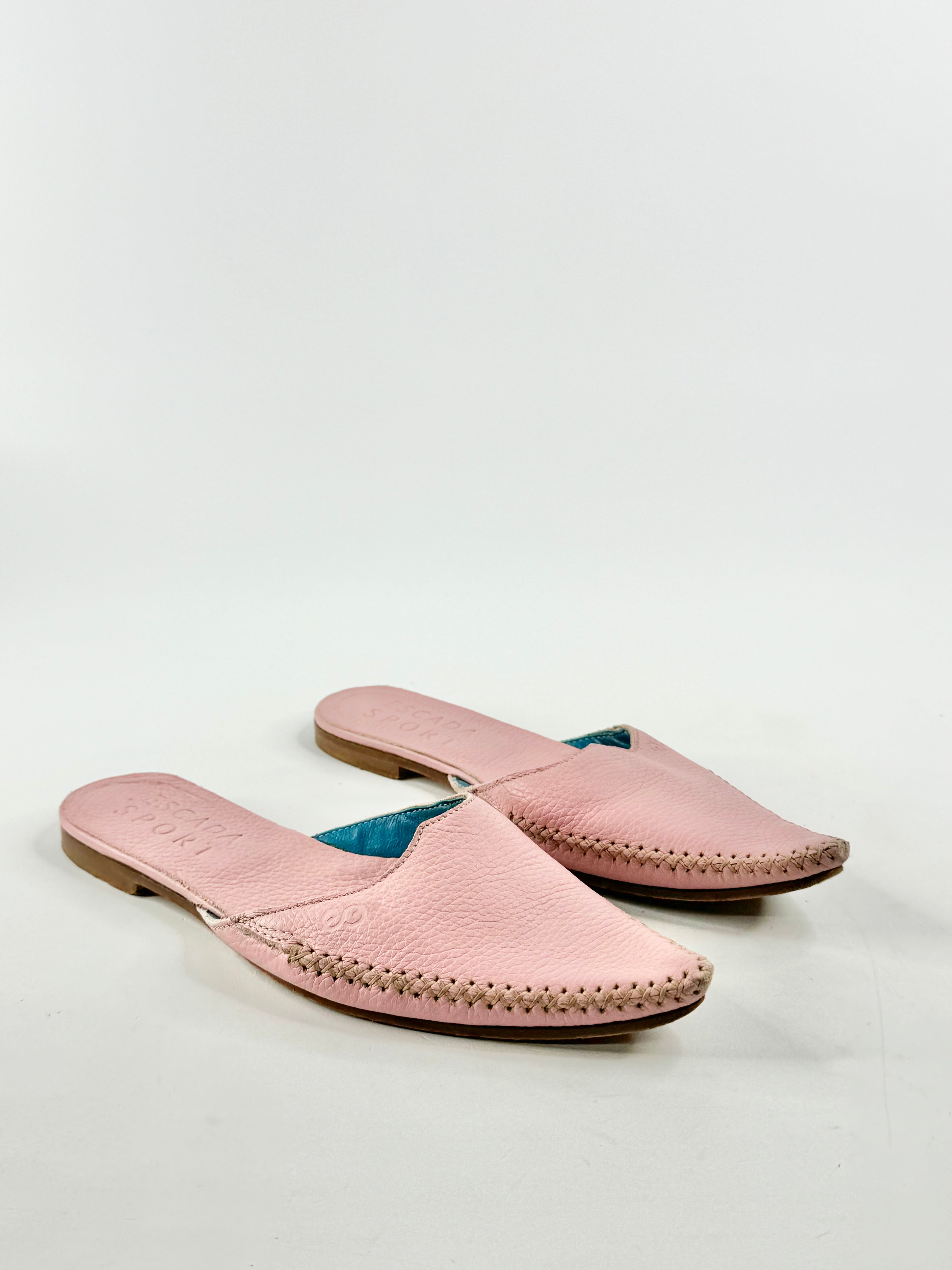 A pair of pink pointed mules with beige stitching on a white background