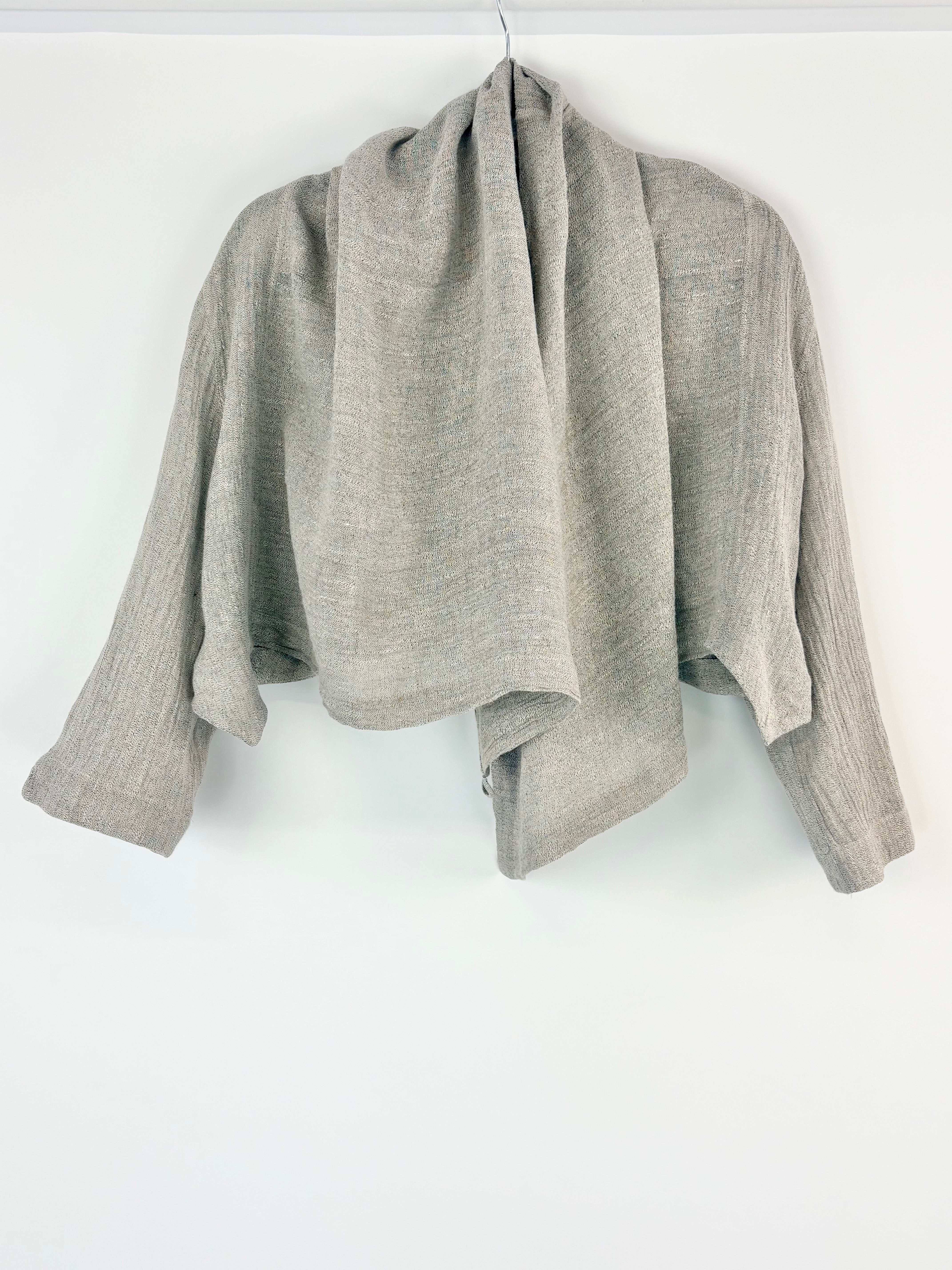 Grey shrug on a hanger against a white background