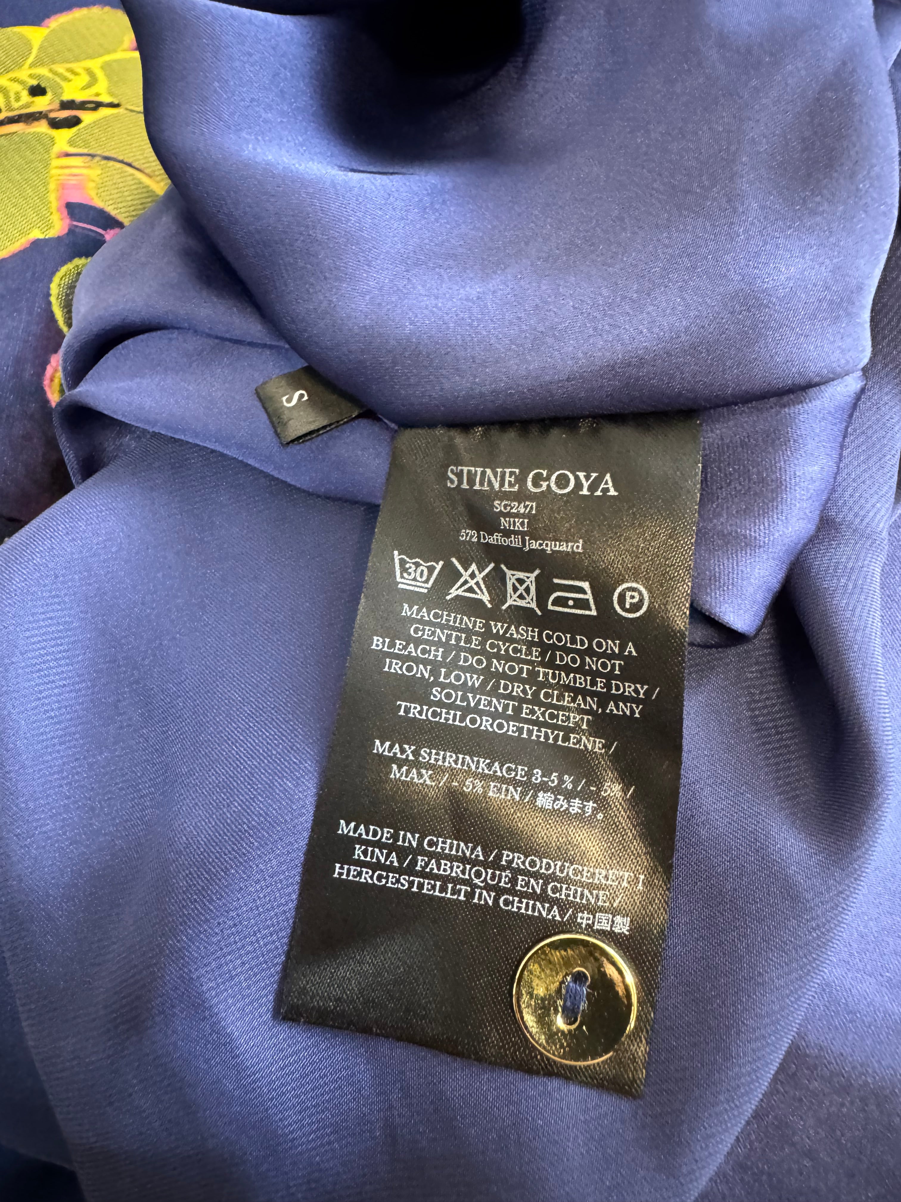 Close-up of a Stine Goya label on a piece of purple fabric.