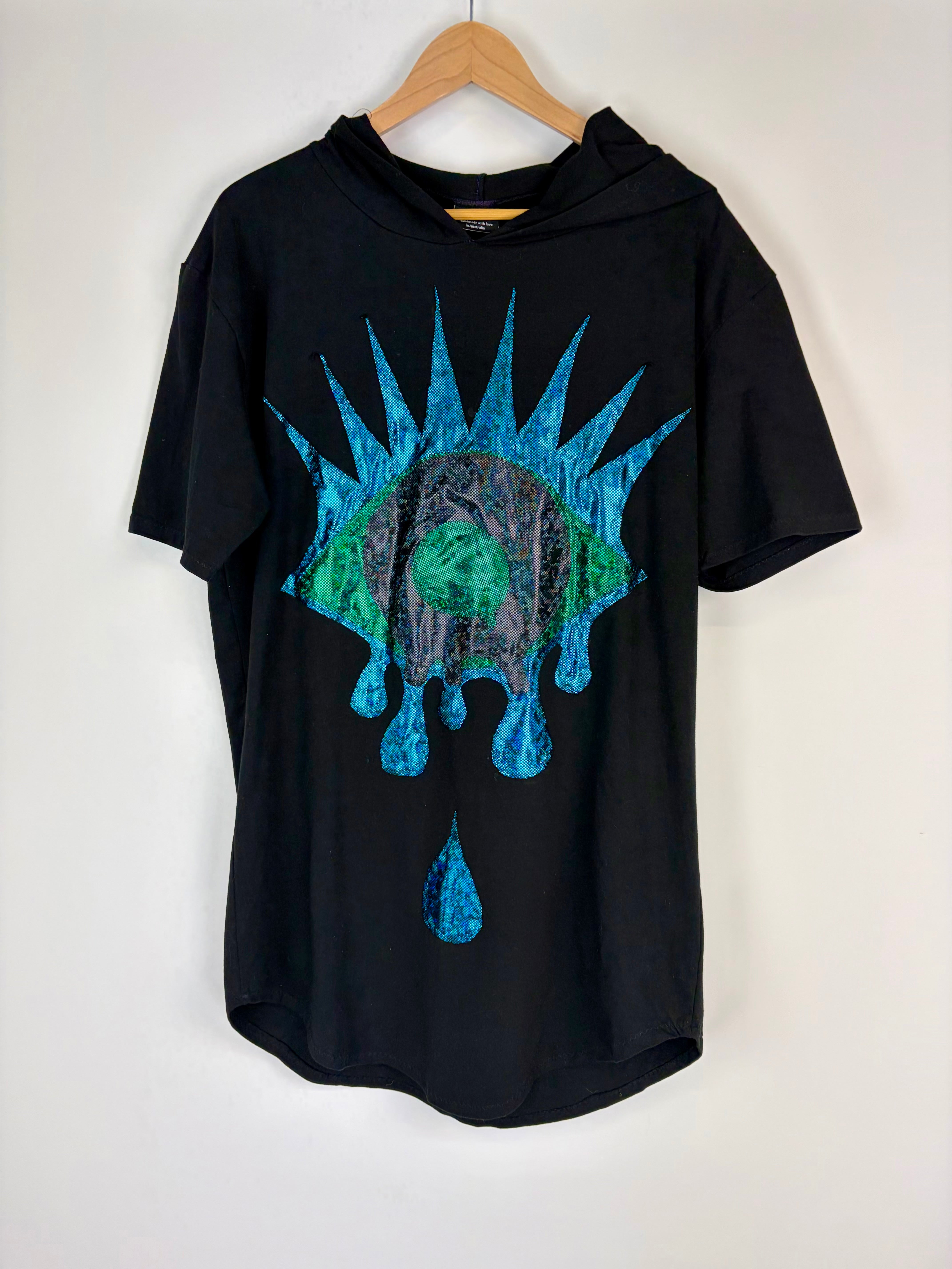Black t-shirt with blue and green graphic design on a hanger against a white background