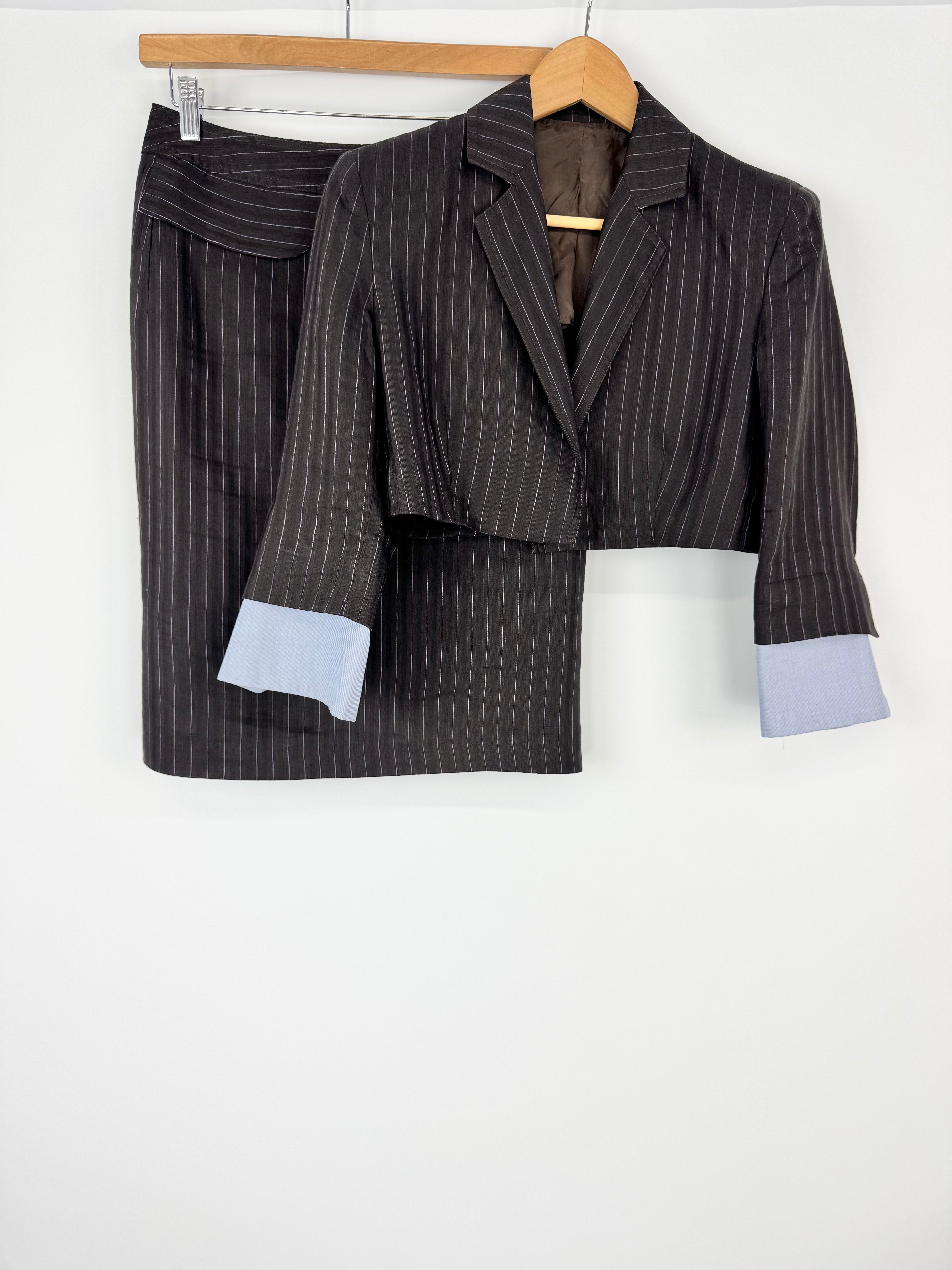 Pinstripe suit jacket and skirt set on a hanger against a white background