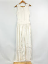 White sleeveless dress on a wooden hanger against a white background