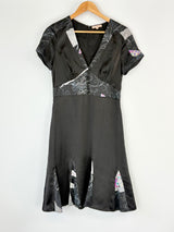 Black Fleur Wood dress with floral patterns on a hanger against a white background