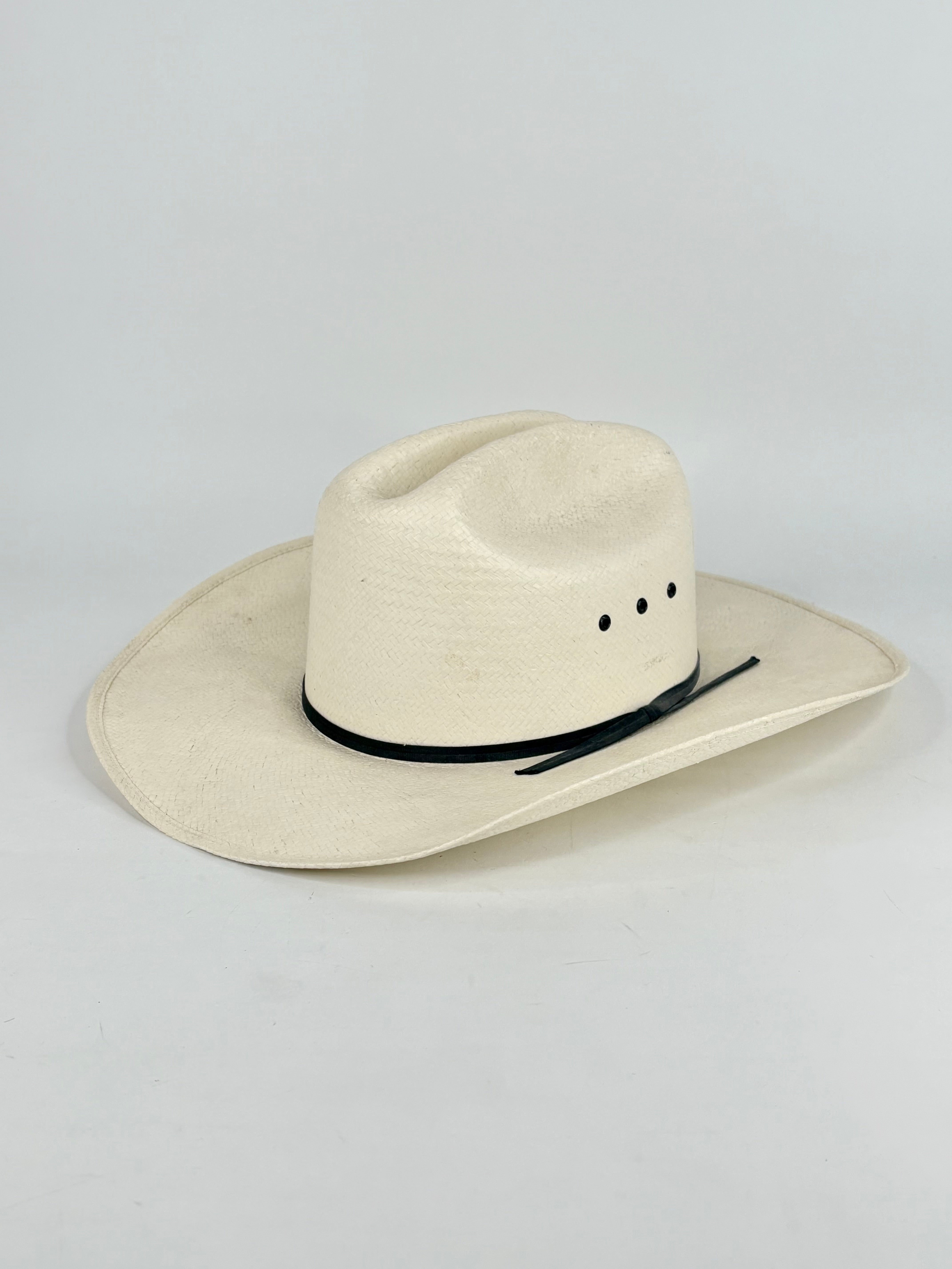 White cowboy hat with a black band on a light gray background