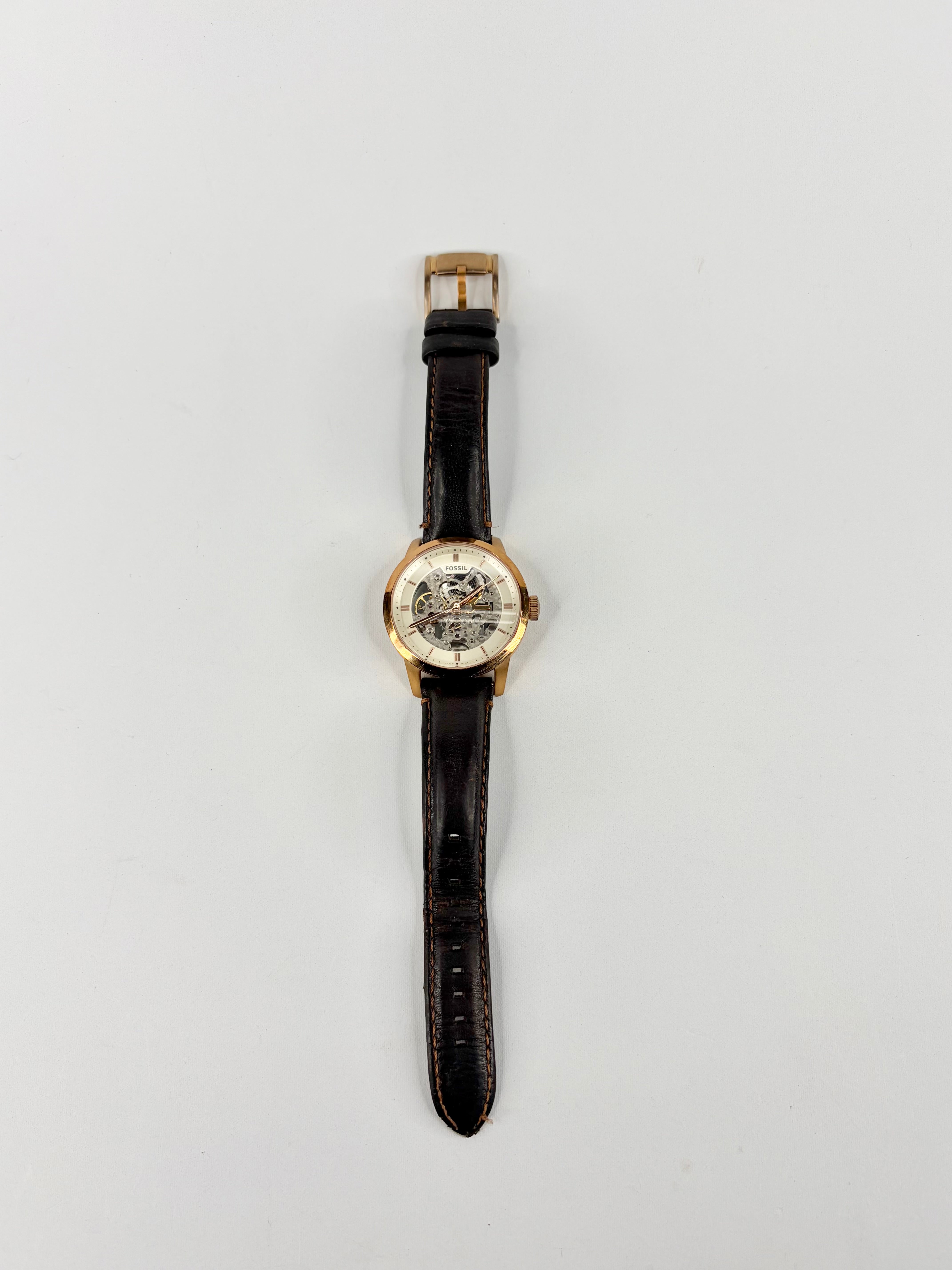 Wristwatch with black strap and gold case on a light gray background