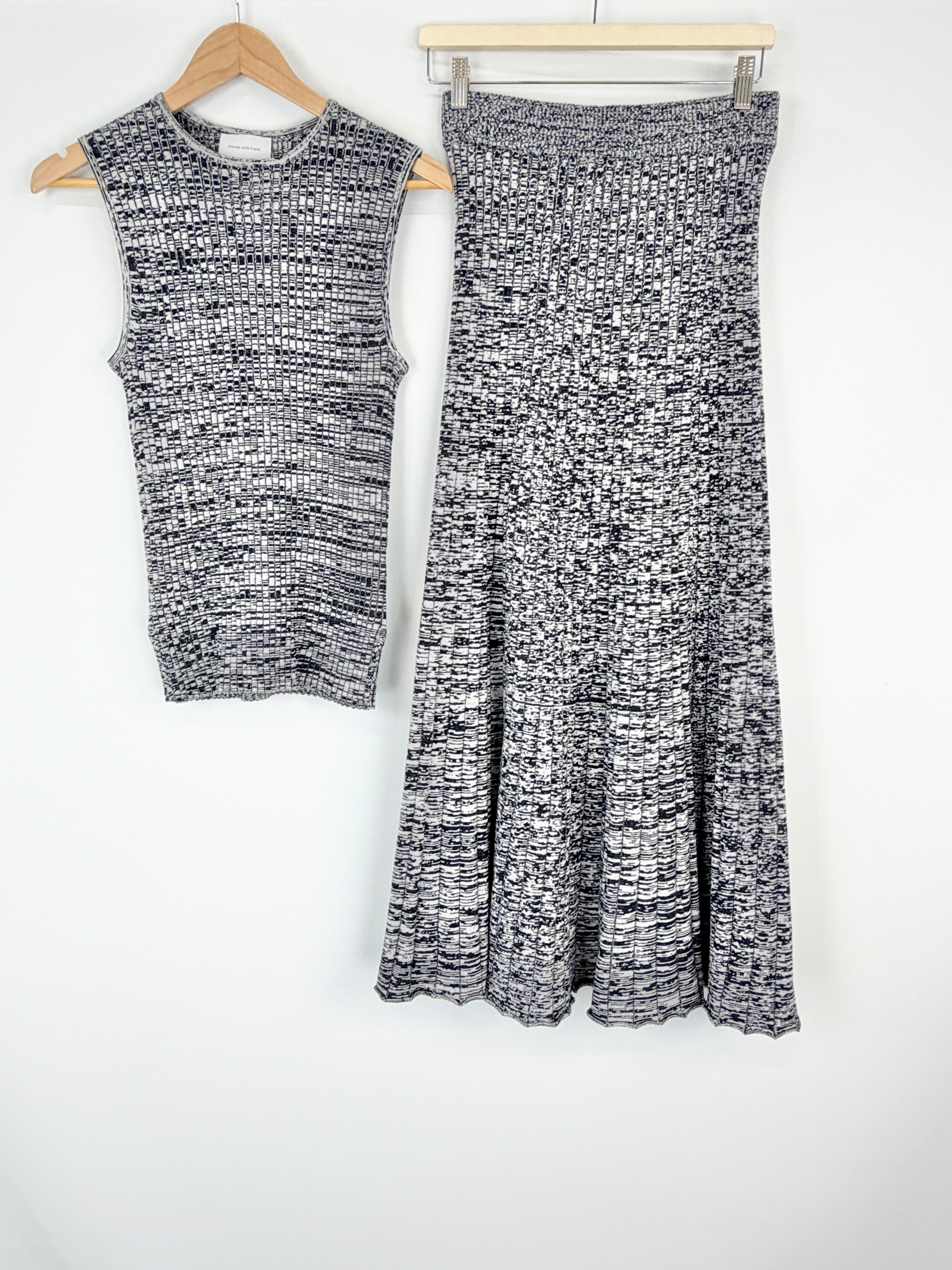 Black and white sleeveless top and skirt set on hangers against a white background