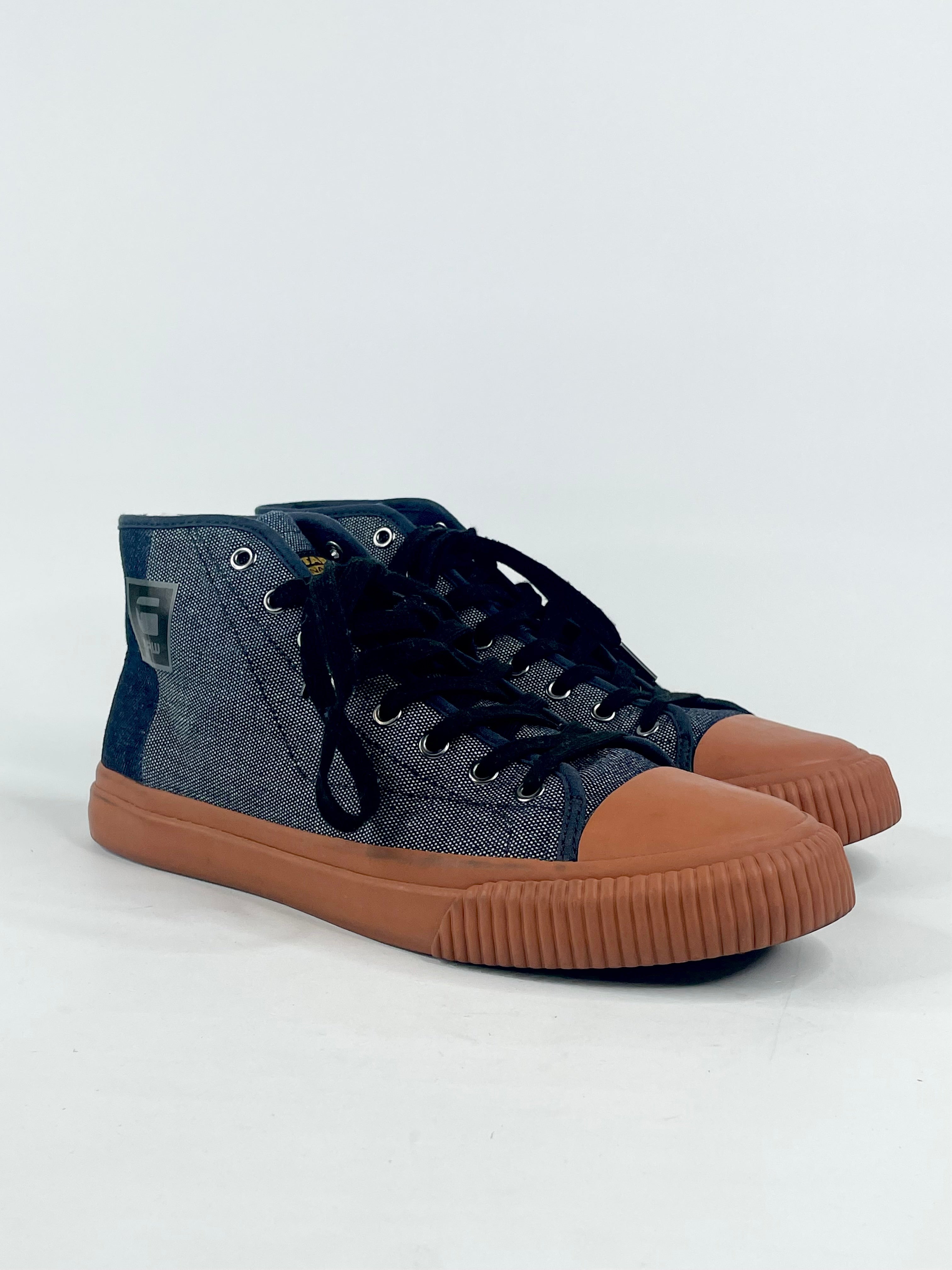 A pair of dark blue denim high-top sneakers with brown sole, laces, and minor box wear.