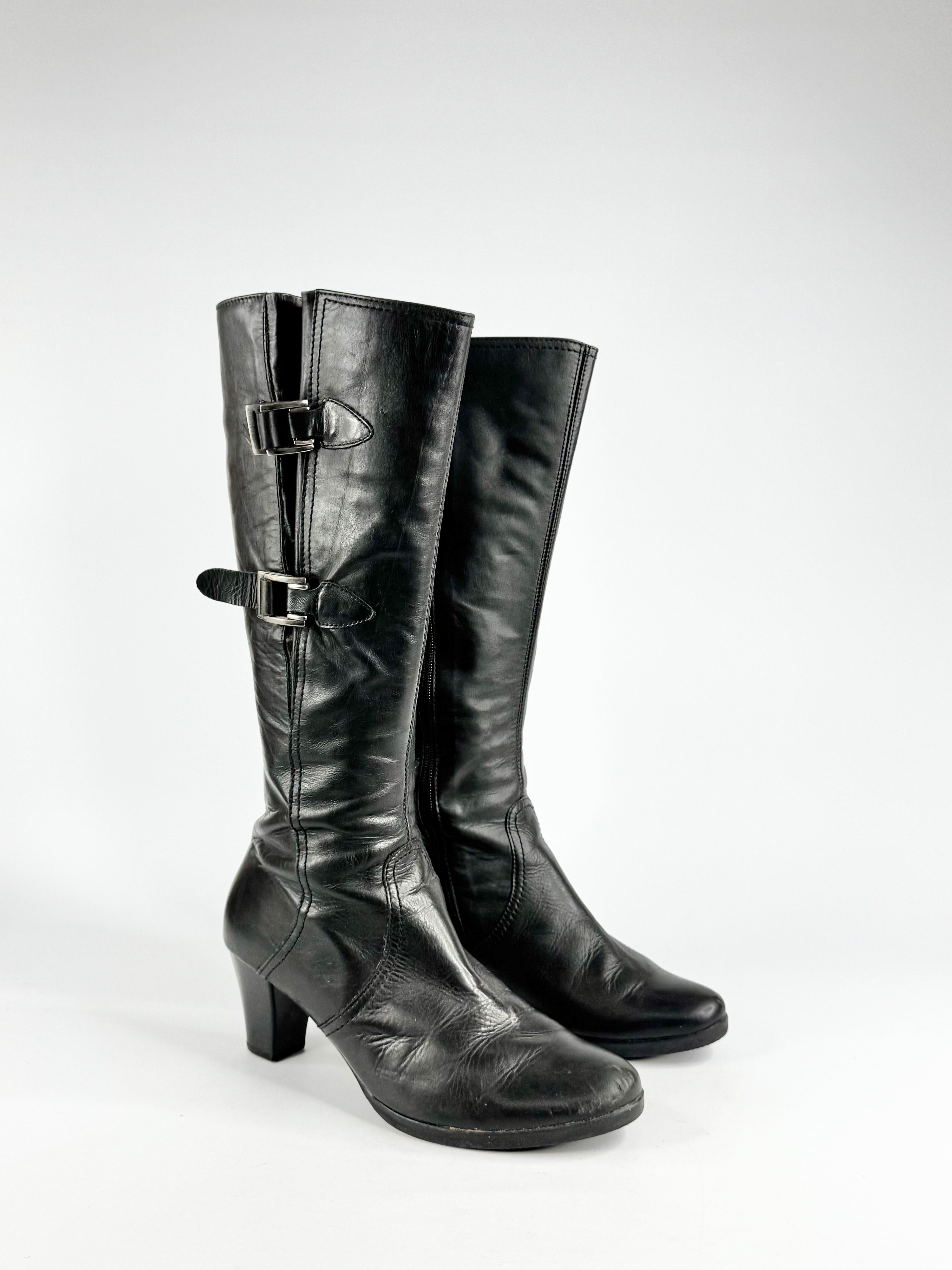Pair of black knee-high boots with buckles on a white background