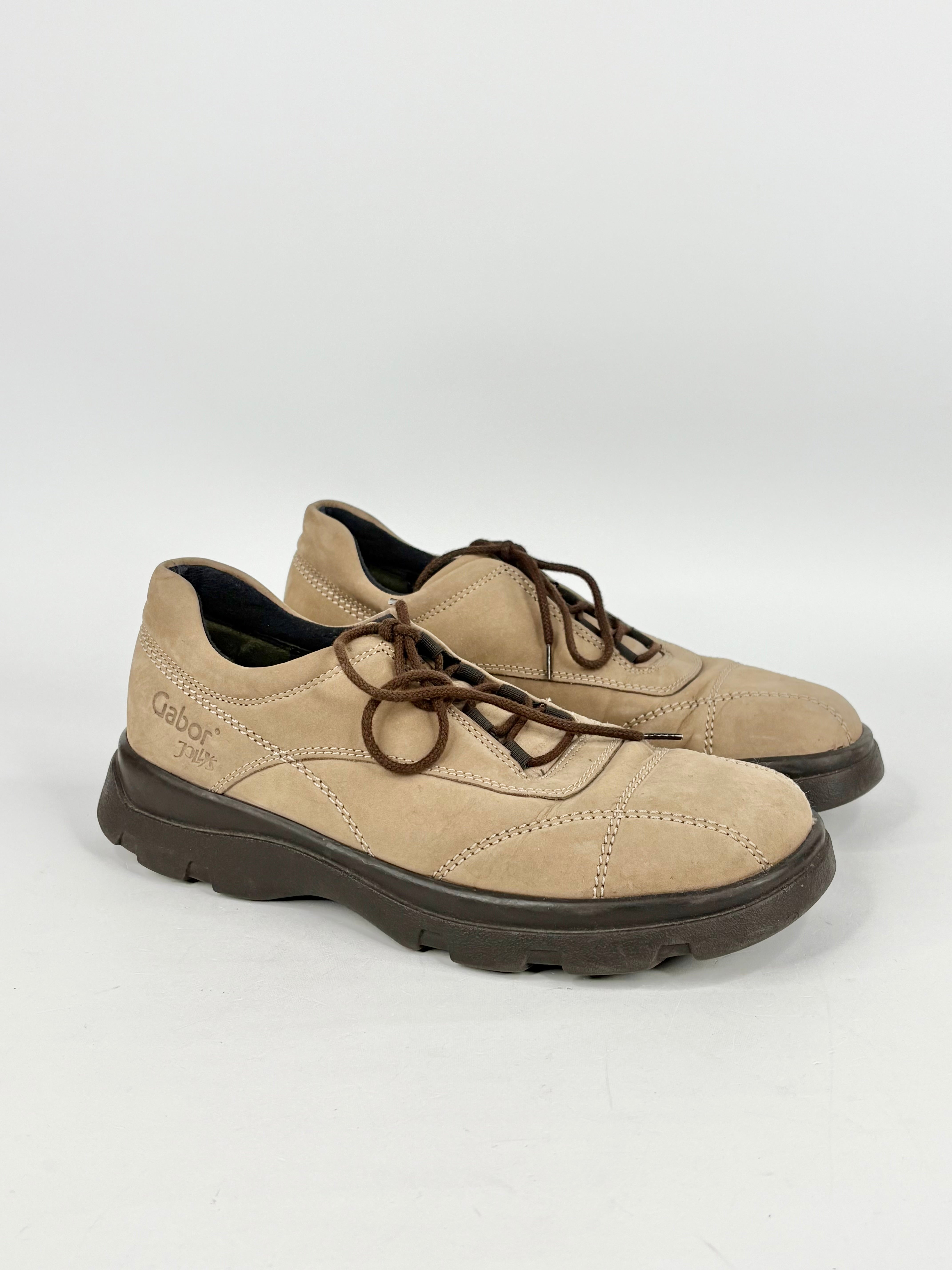 Pair of beige shoes with black soles on a white background