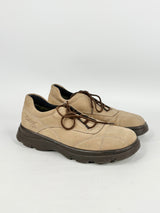 Pair of beige shoes with black soles on a white background