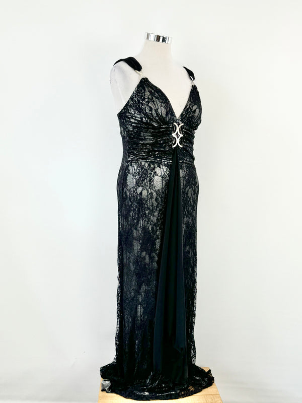 Black lace formal dress with metallic silver fabric and jewel encrusted 'x' shaped hardware on the sleeves, displayed on a mannequin.