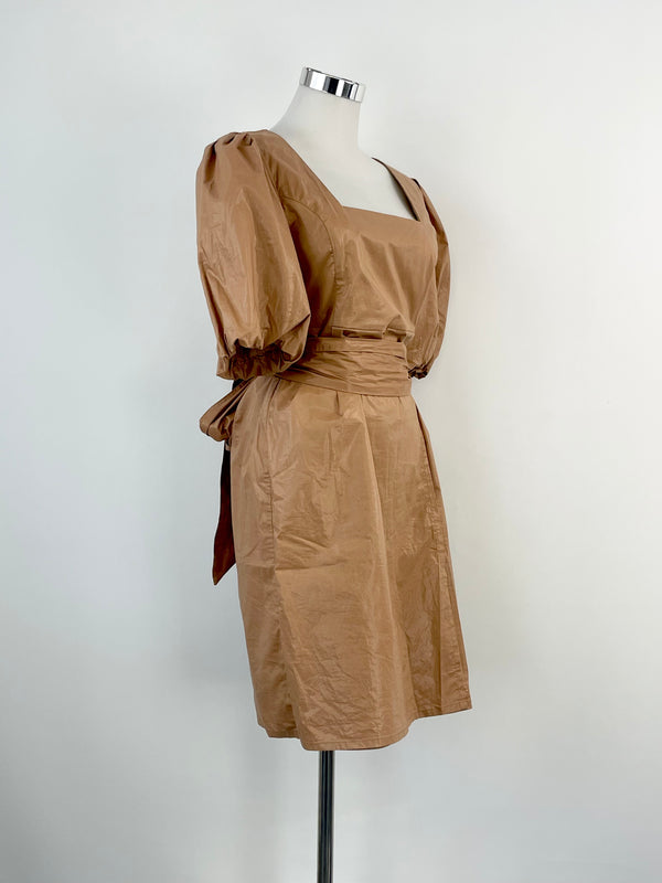 A taupe colored midi dress with puffed shoulders and a waist tie, displayed on a mannequin.
