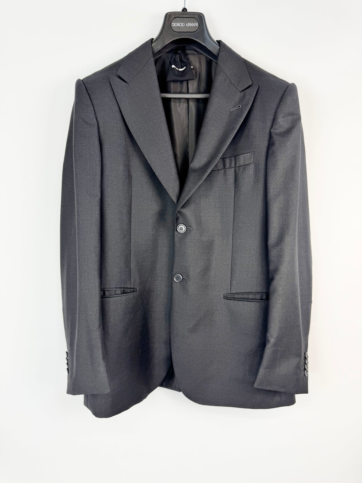 Gray suit jacket on a hanger against a white background