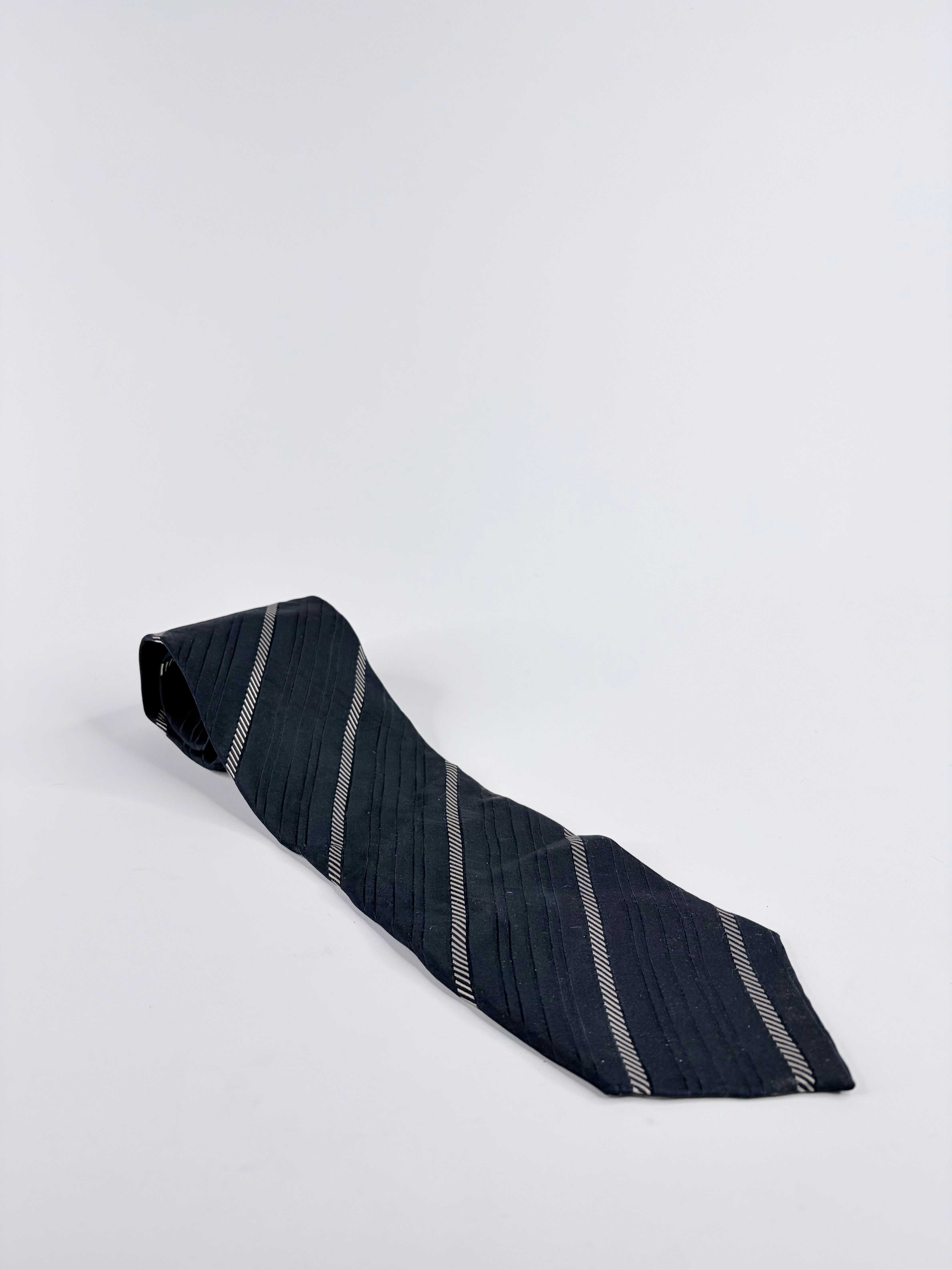Navy blue tie with white stripes on a light gray background