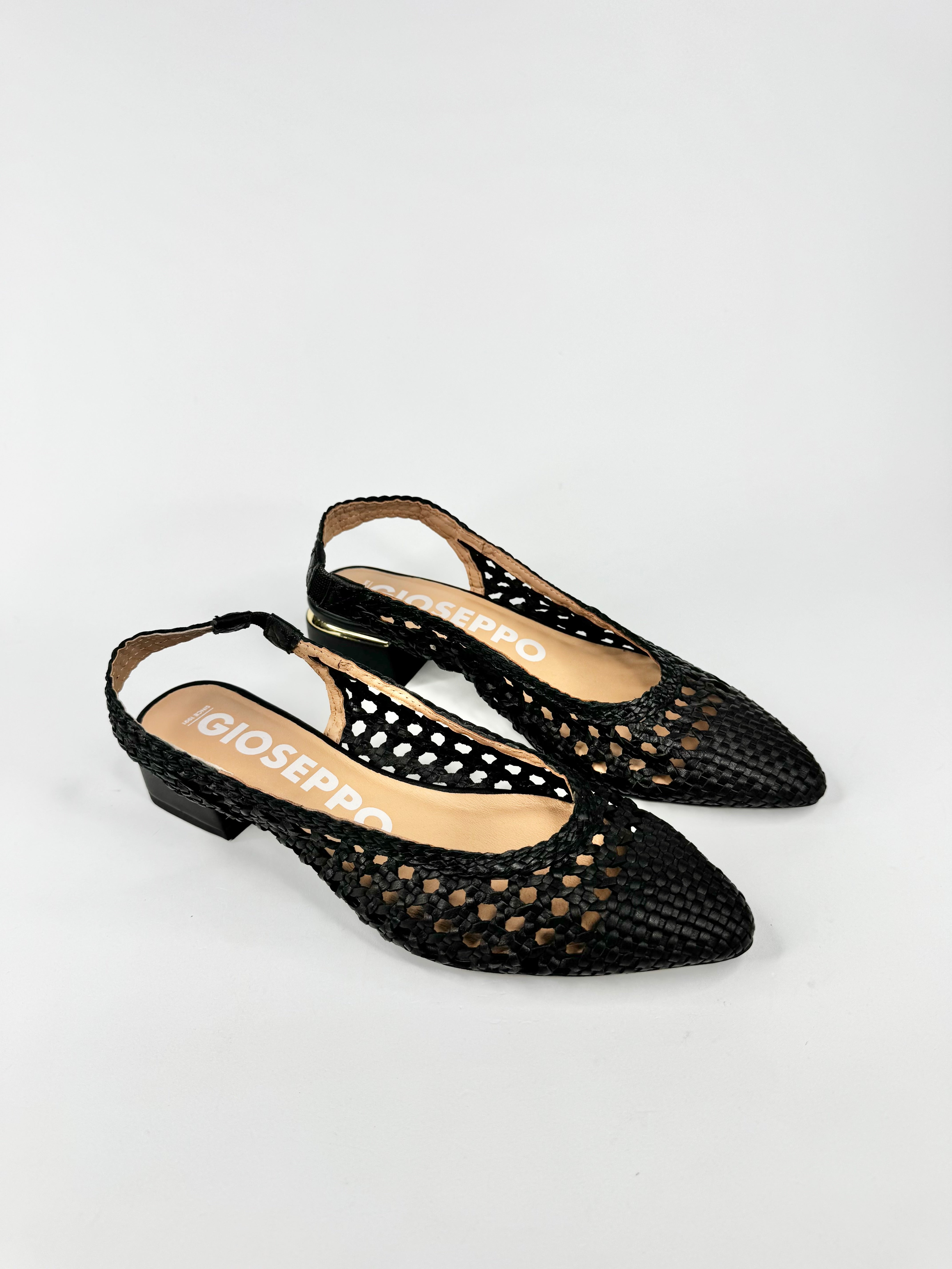 Black pointed-toe shoes with cut-out design on a light gray background