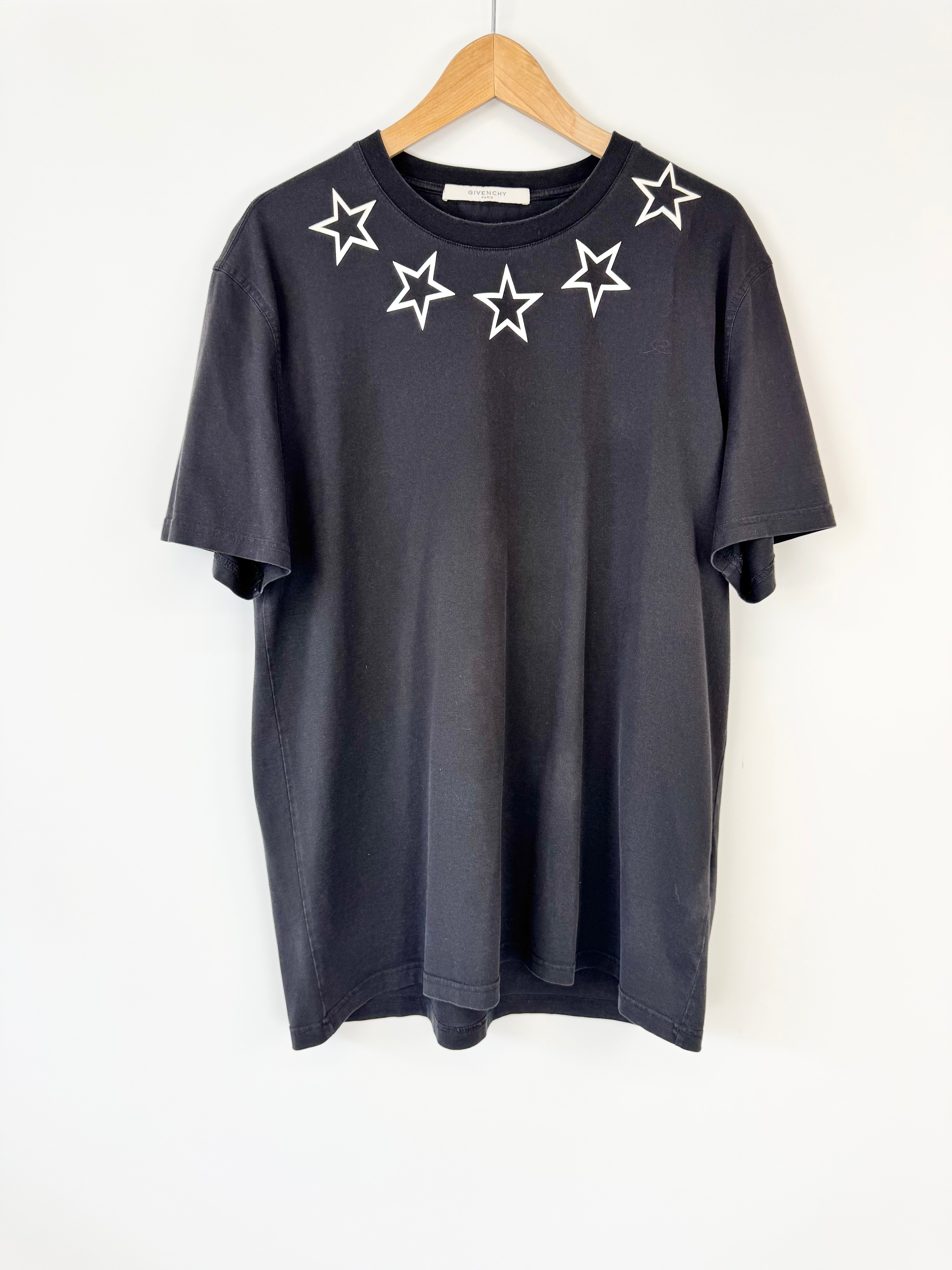 Black t-shirt with star designs on a wooden hanger against a white background