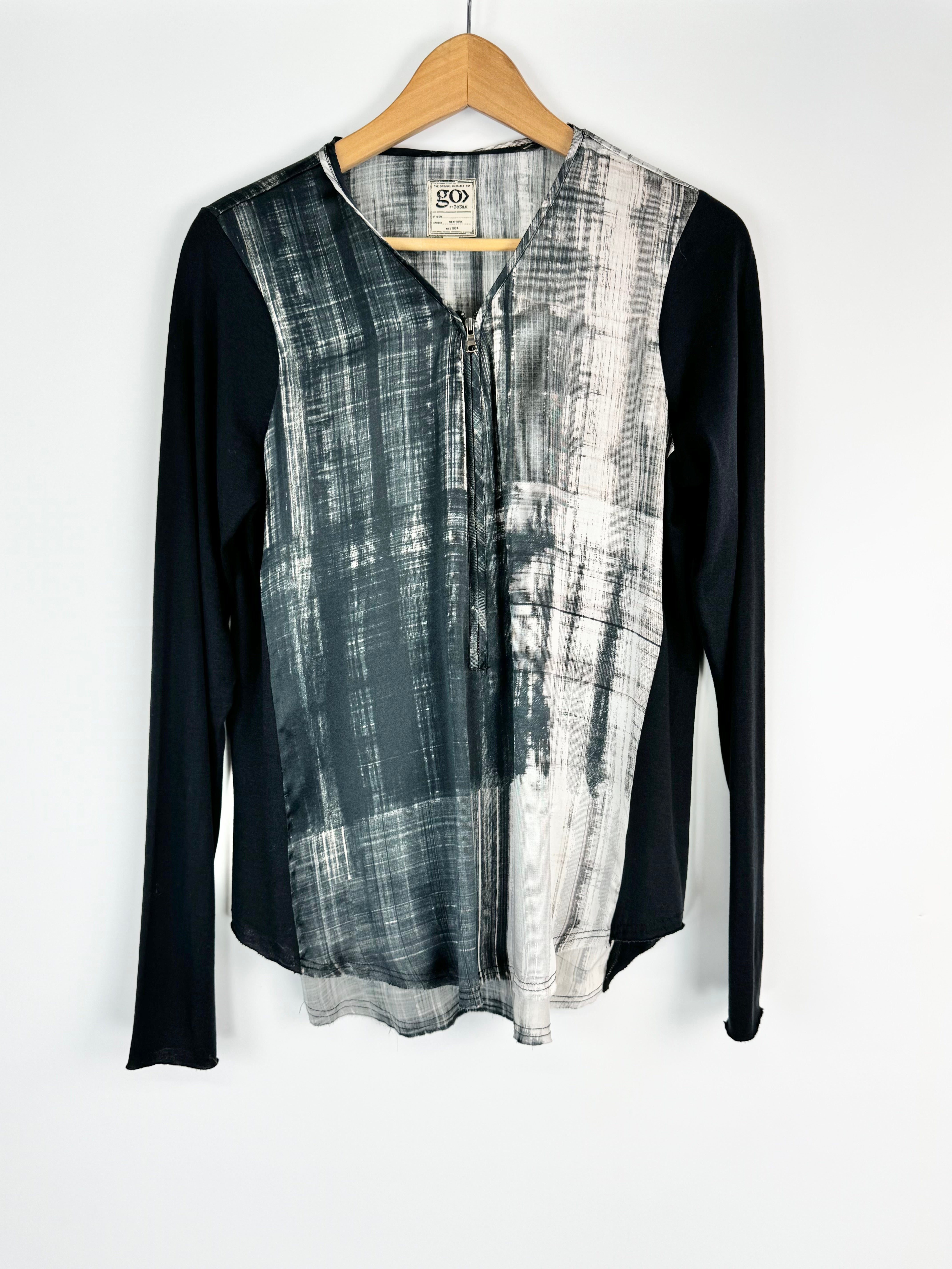 Plaid shirt with black sleeves on a hanger against a white background