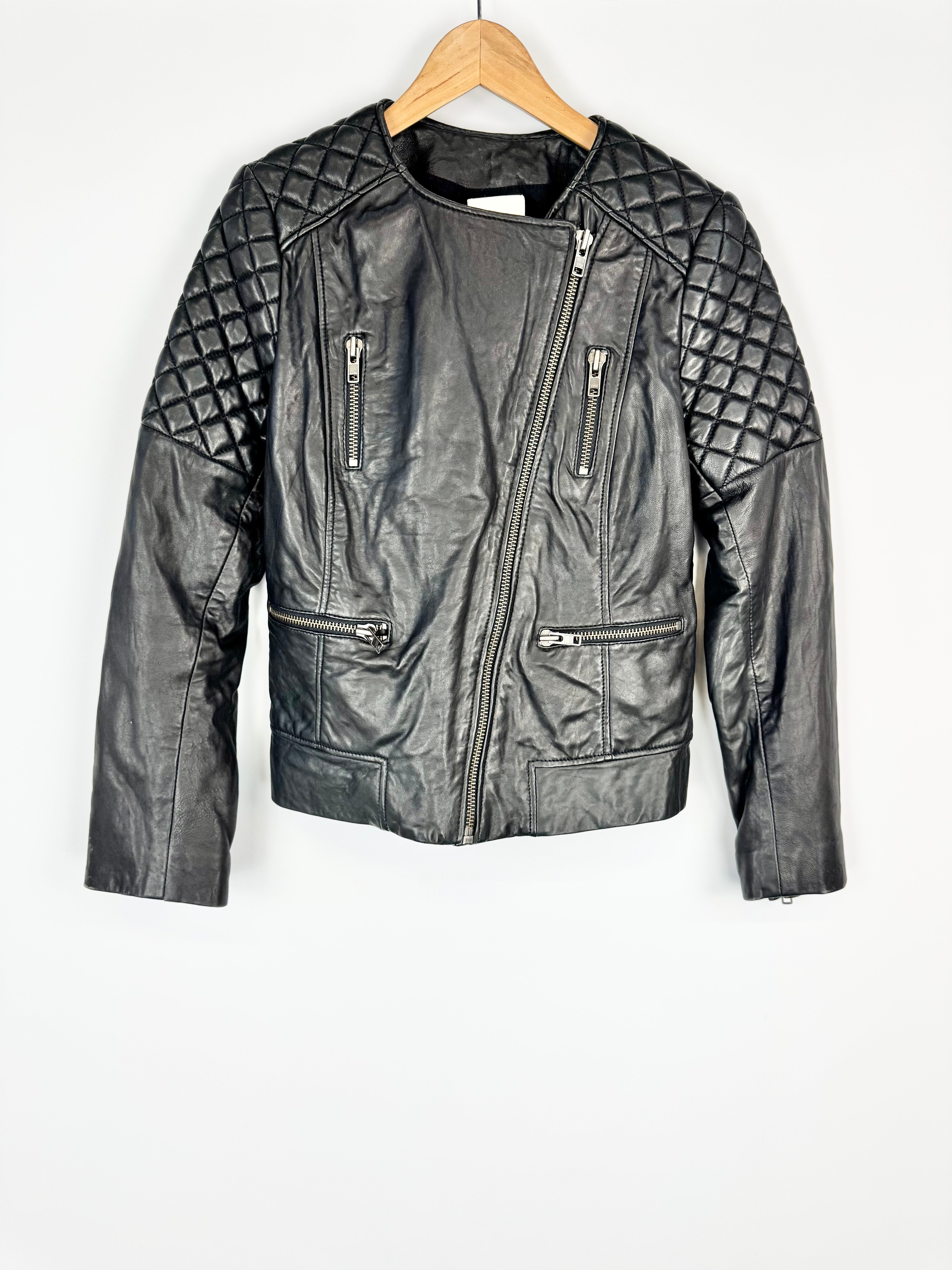 Black leather jacket with quilted shoulder design on a hanger against a white background