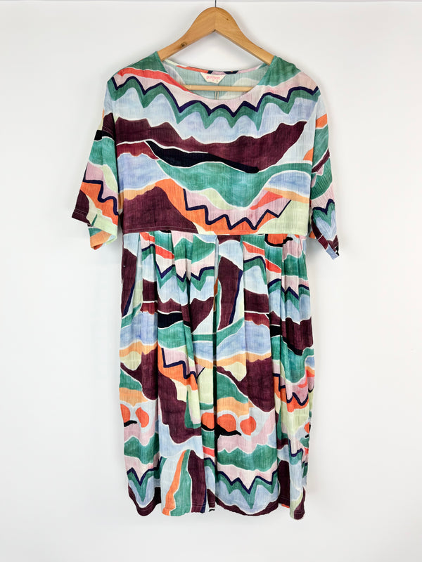 Colorful patterned dress on a hanger against a white background