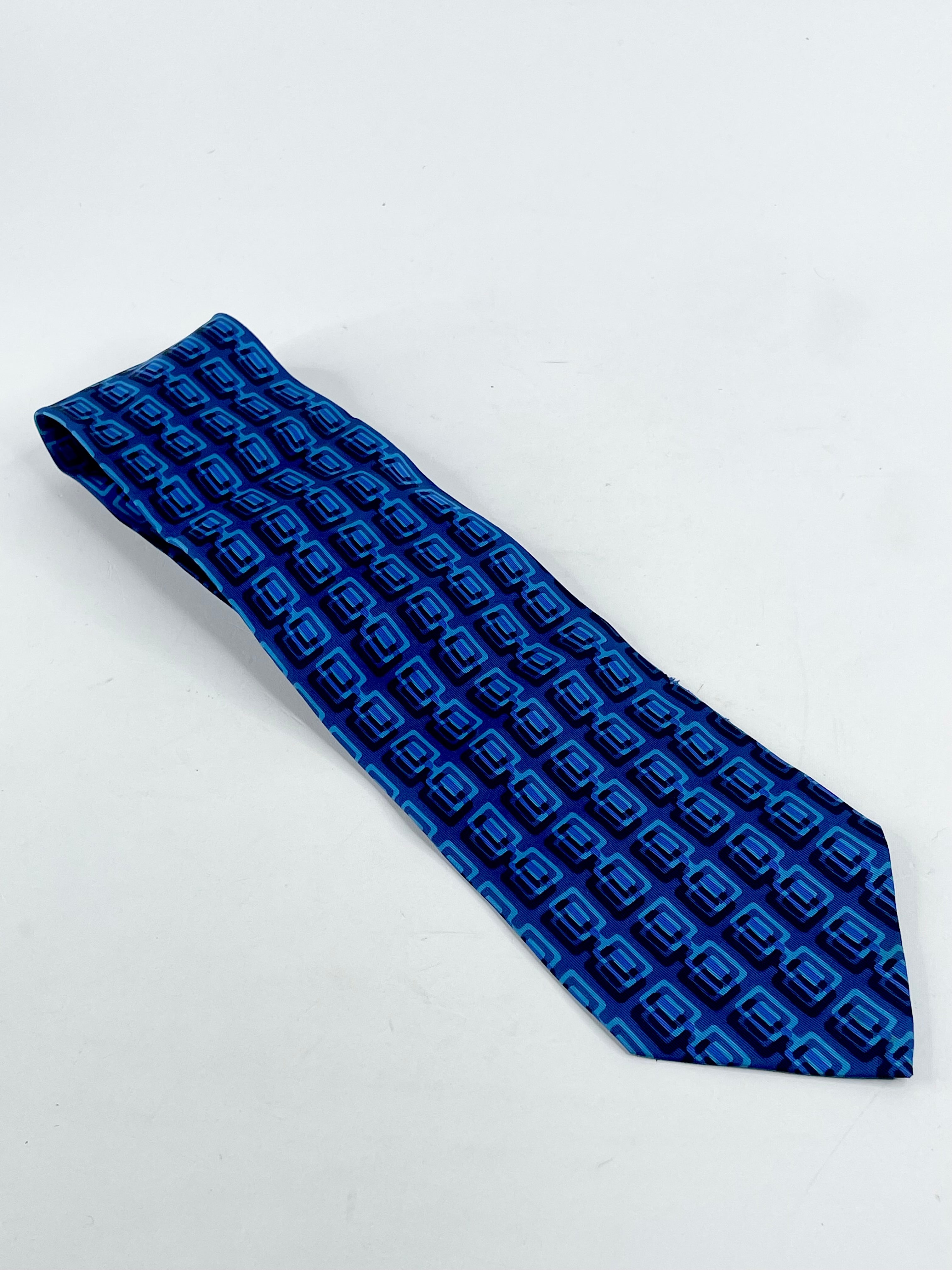 A dark blue silk tie with a geometric pattern, displayed on a plain background.