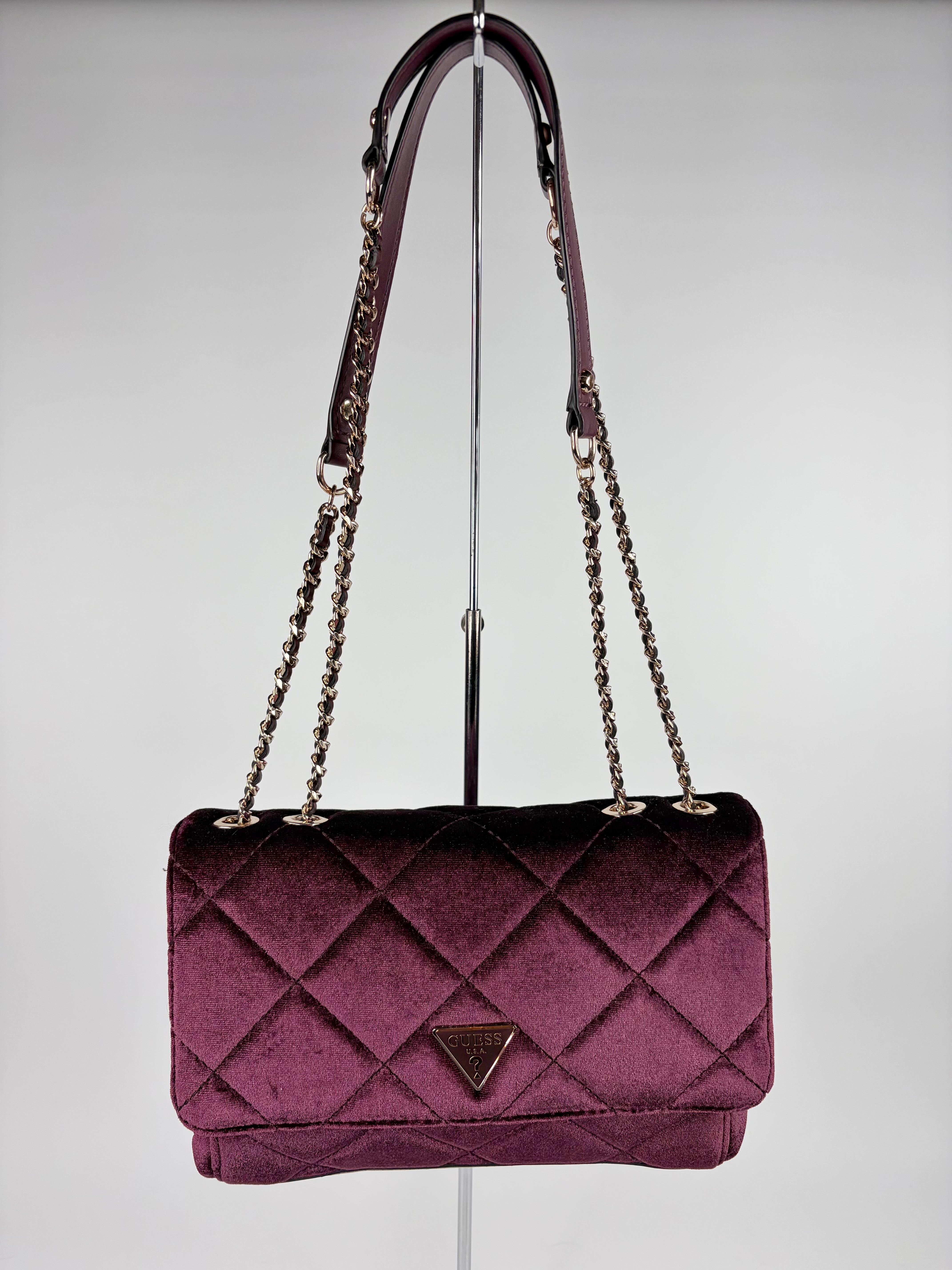 Purple quilted handbag with chain strap on a gray background